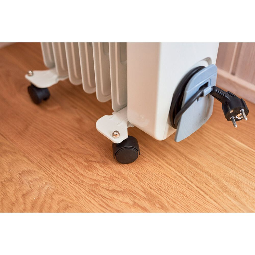 Ein weißer Heizkörper auf Rädern steht auf einem Holzboden. Ein Stecker ist angeschlossen.