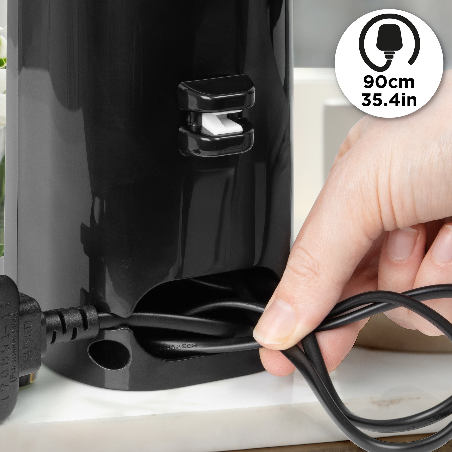 Eine Hand wickelt ein schwarzes Kabel um ein schwarzes Gerät mit einem Stecker.