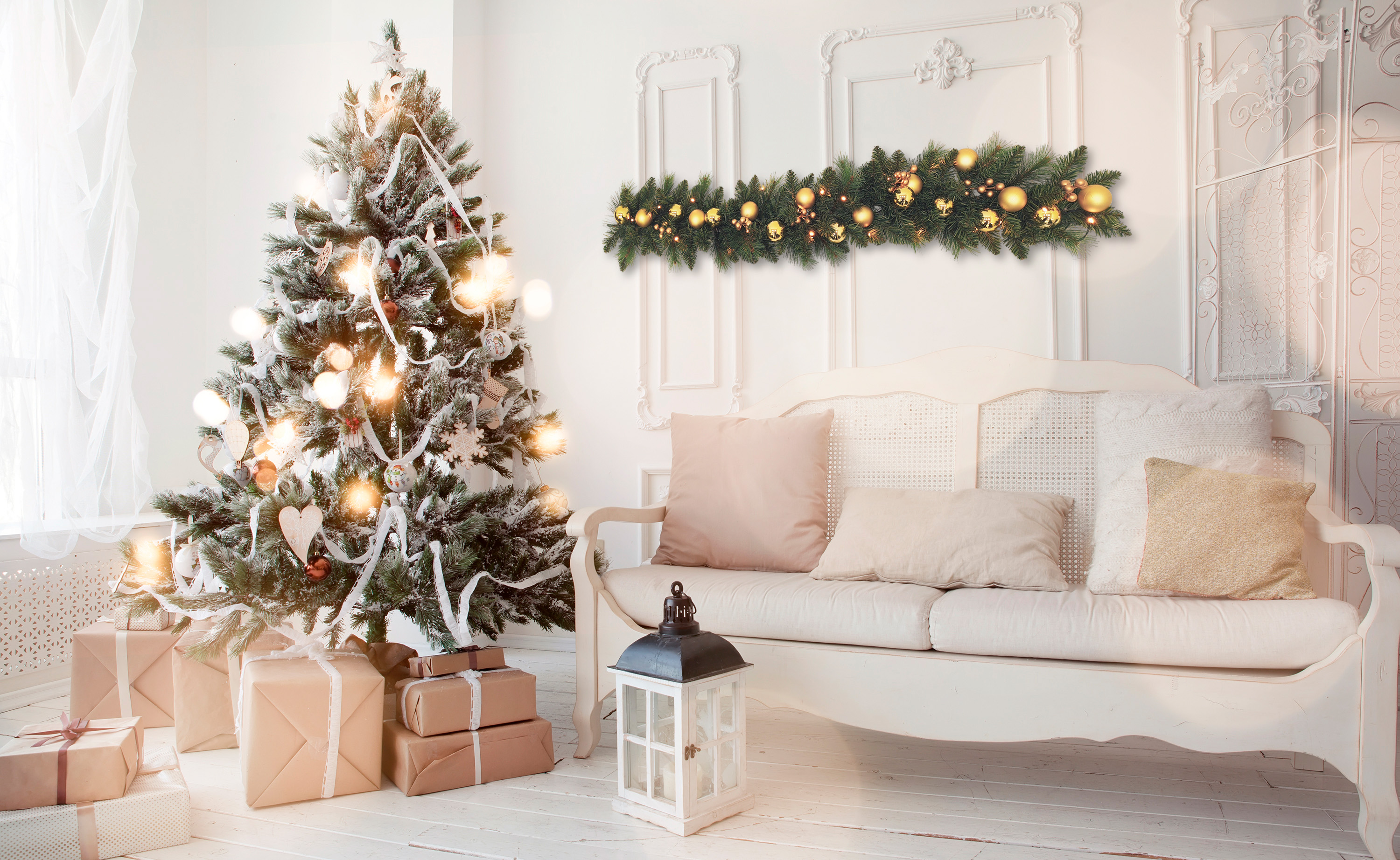 Ein geschmückter Weihnachtsbaum mit Lichtern und Geschenken neben einer weißen Bank.