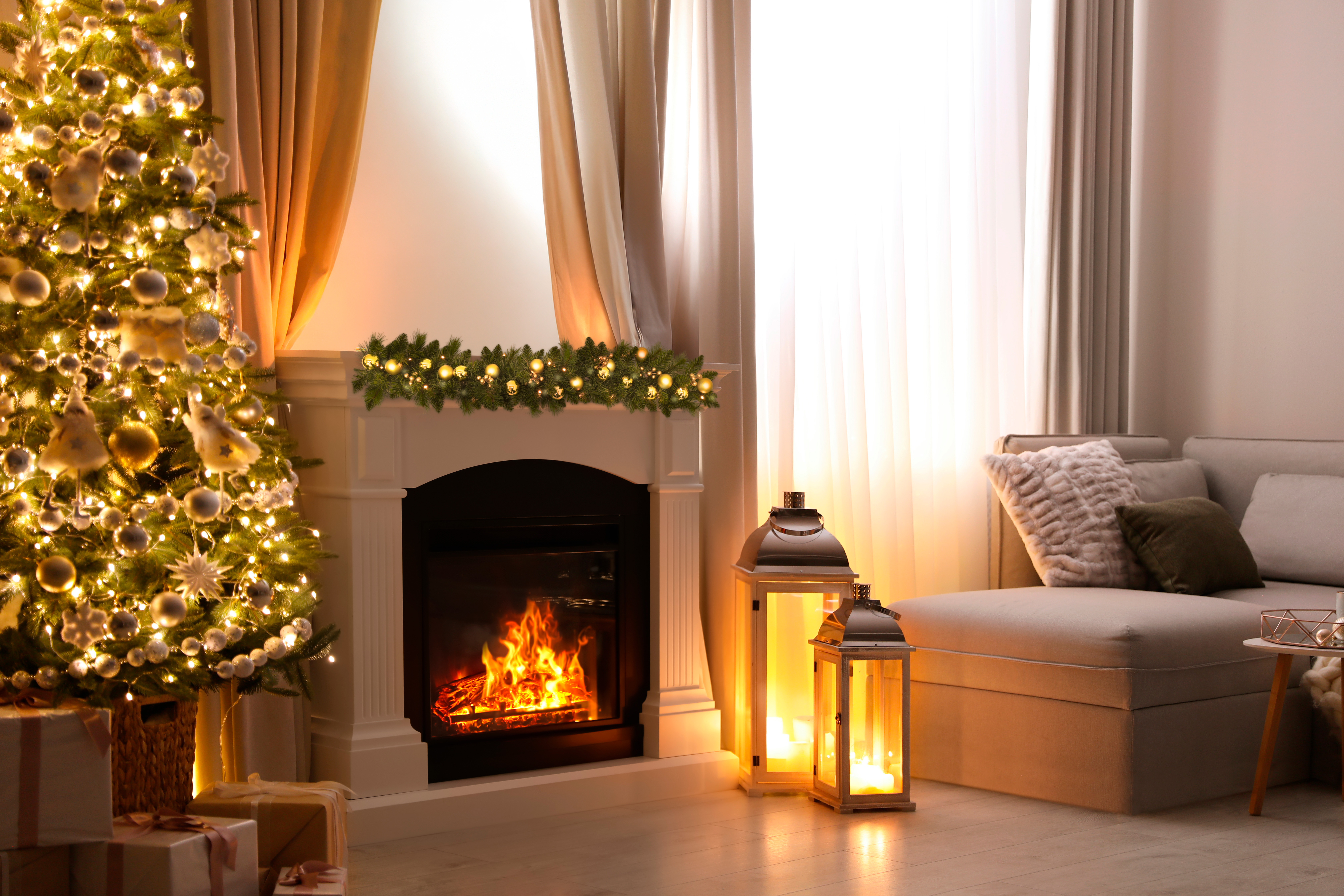Ein geschmückter Weihnachtsbaum neben einem Kamin mit brennendem Feuer.