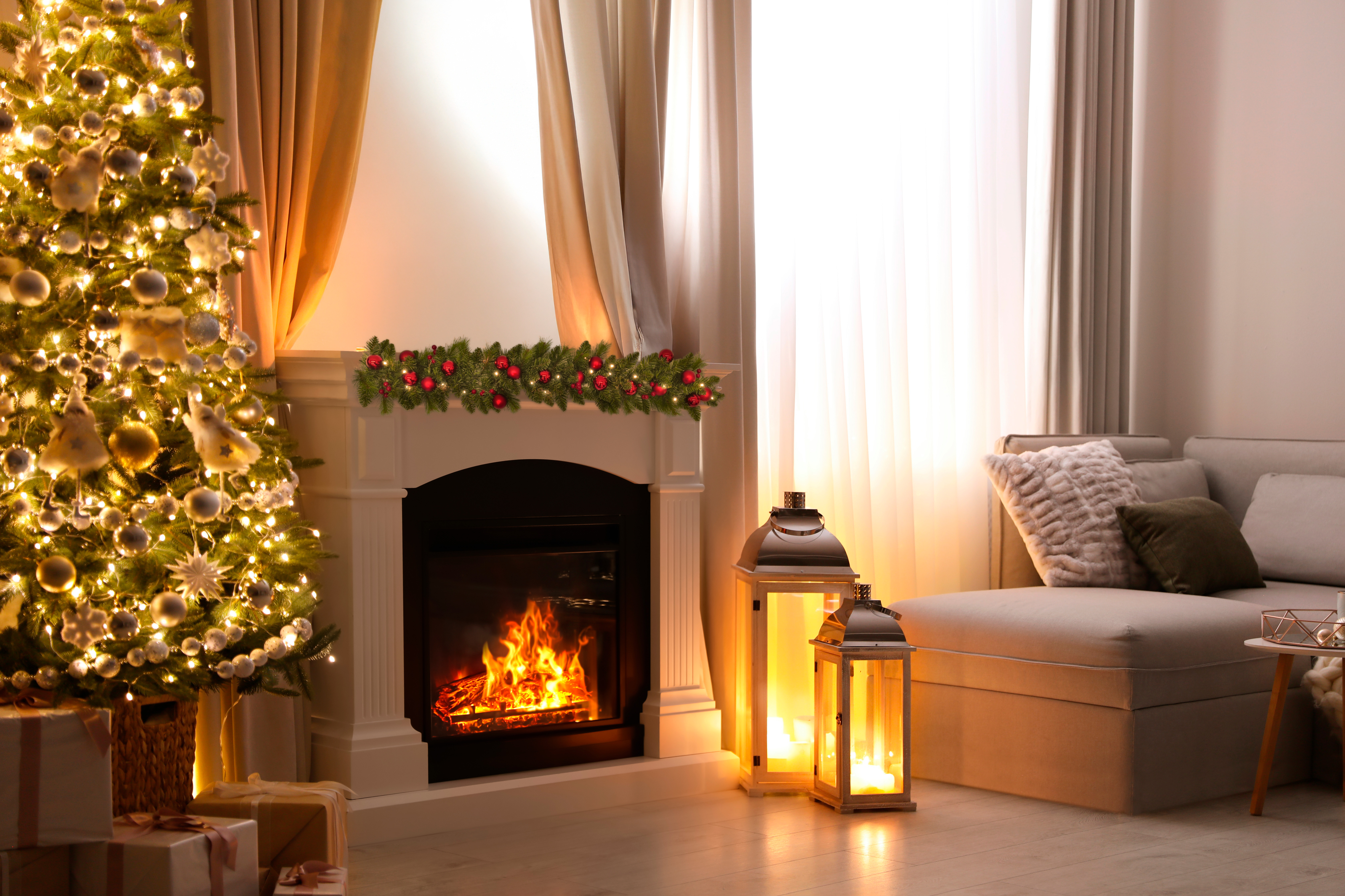 Ein geschmückter Weihnachtsbaum neben einem Kamin mit brennendem Feuer.