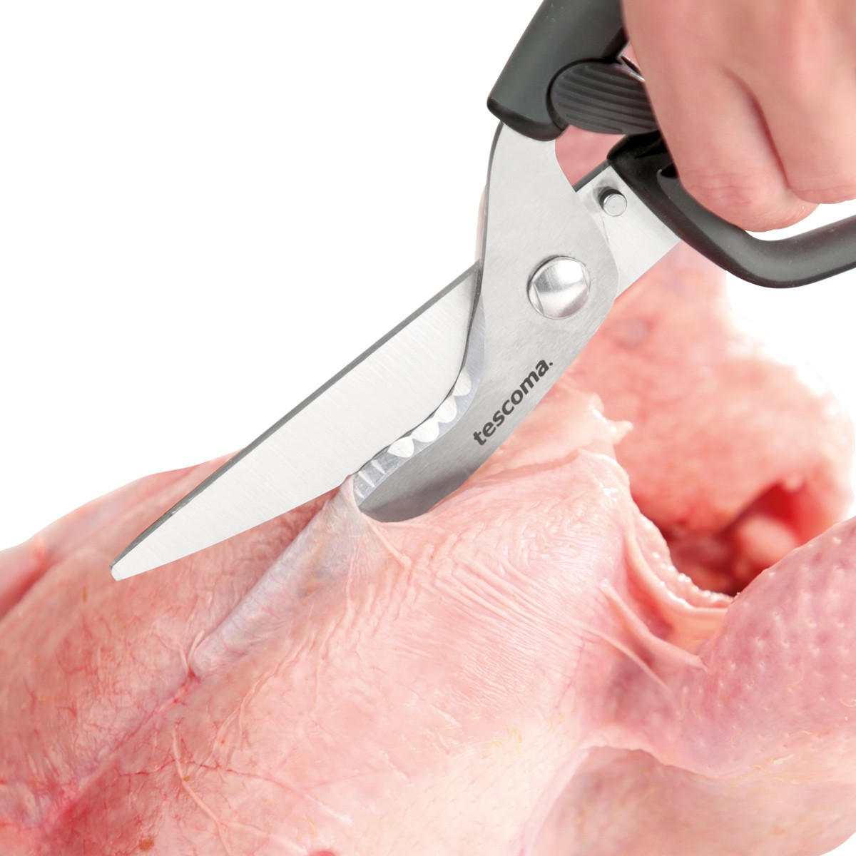 Eine Hand benutzt eine Schere, um ein rohes Huhn zu schneiden.