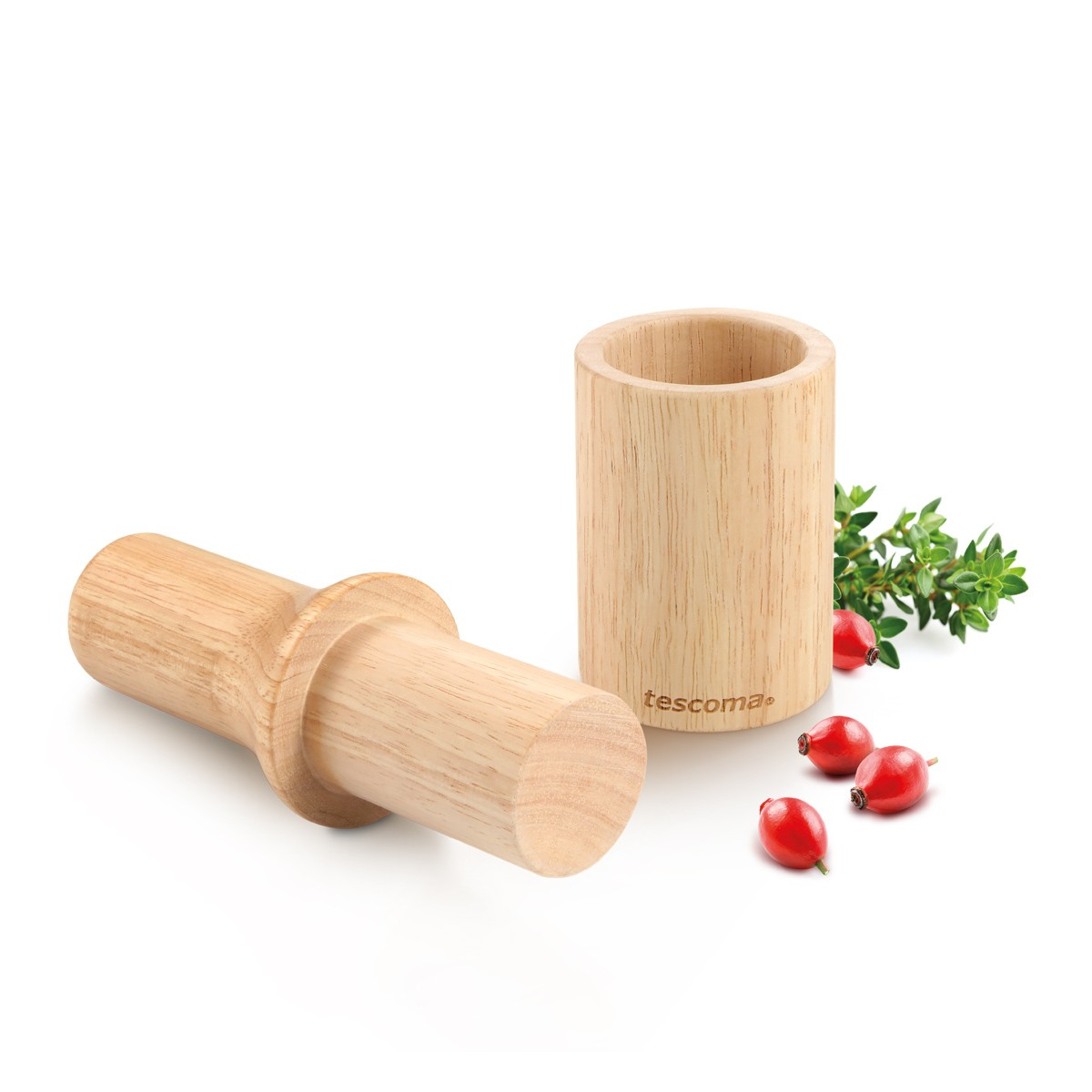 Ein hölzerner Mörser mit Stößel und Hagebutten.
