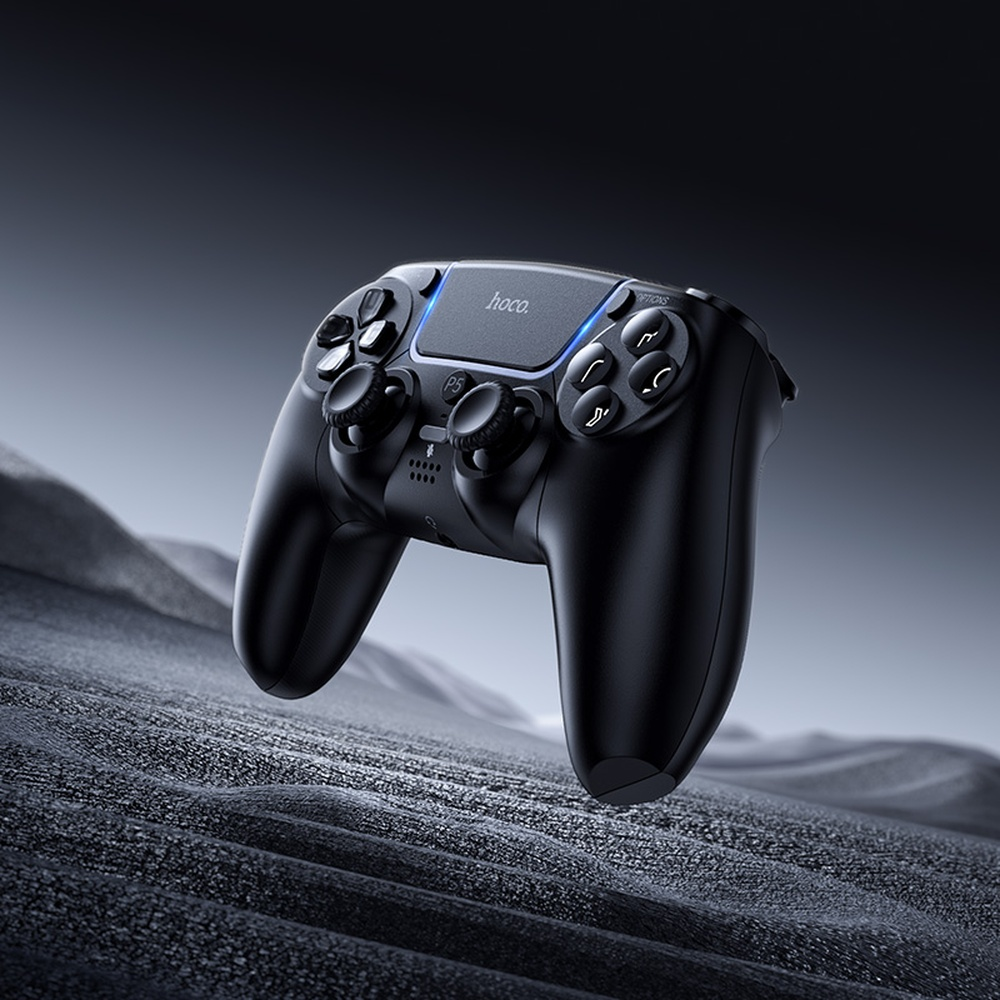 Mando de juego negro con iluminación azul sobre una superficie rocosa oscura.