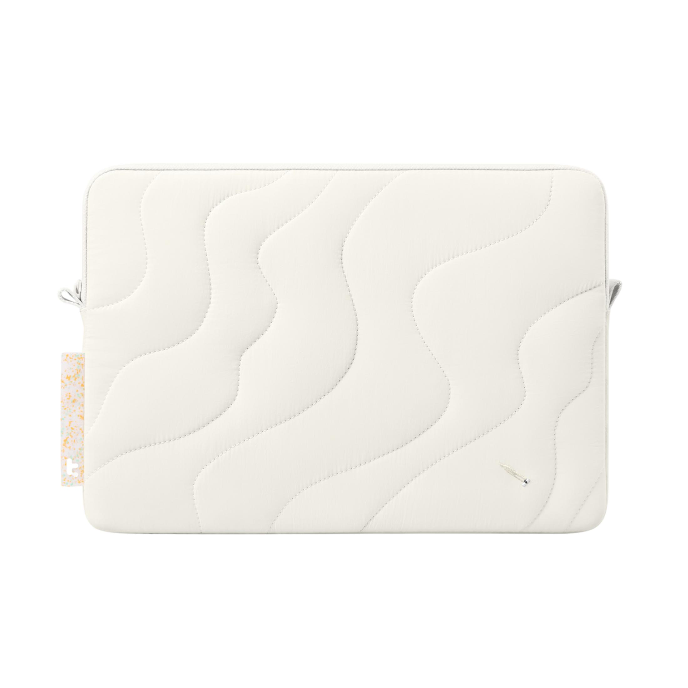 Pikowana, kremowa torba na laptop z zakrzywionymi szwami i małą metką.