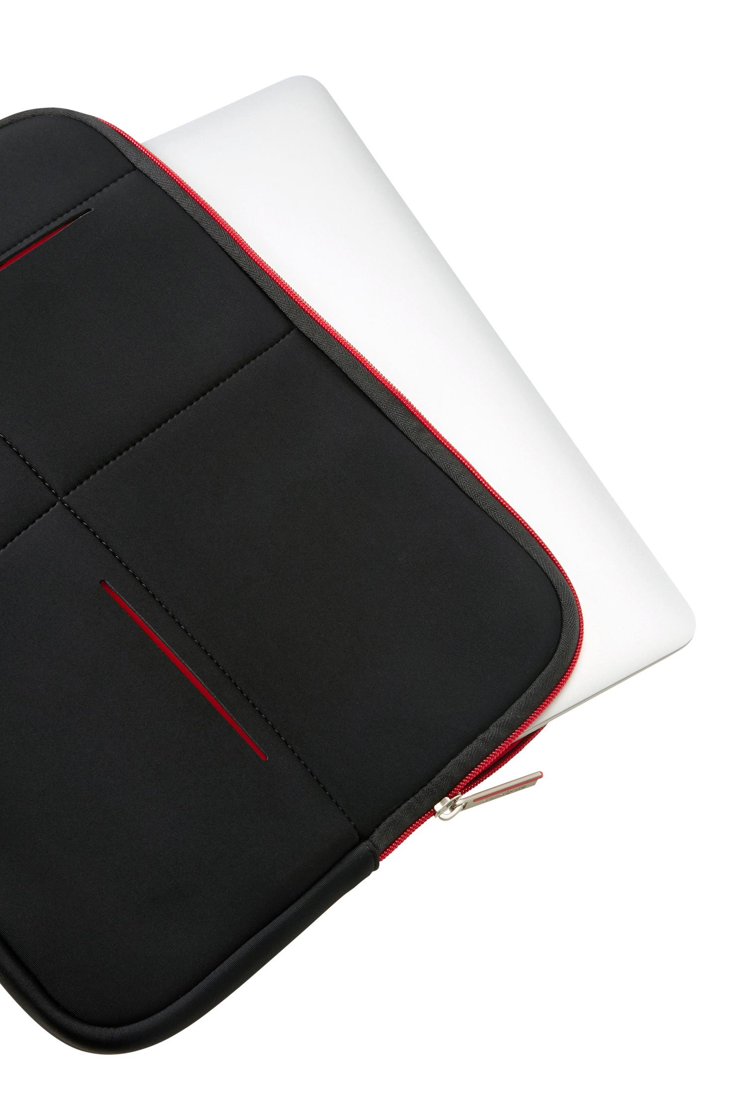 Custodia nera per laptop con cerniera rossa accanto a un laptop argentato.