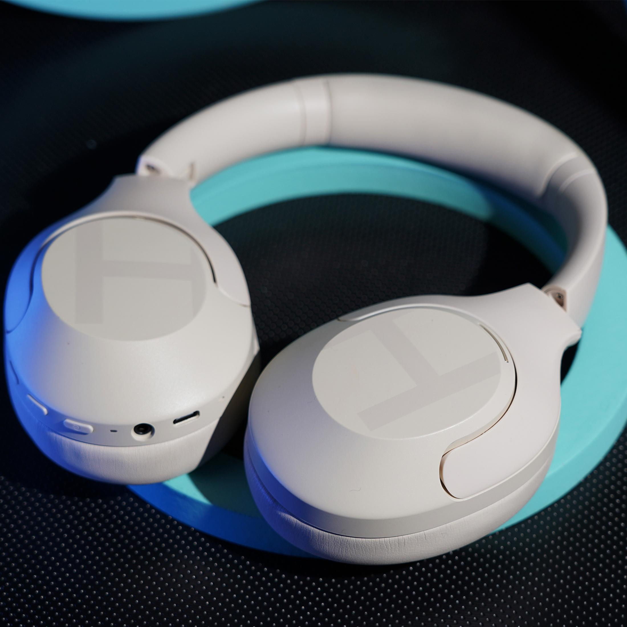 Cuffie bianche su superficie nera con illuminazione blu.