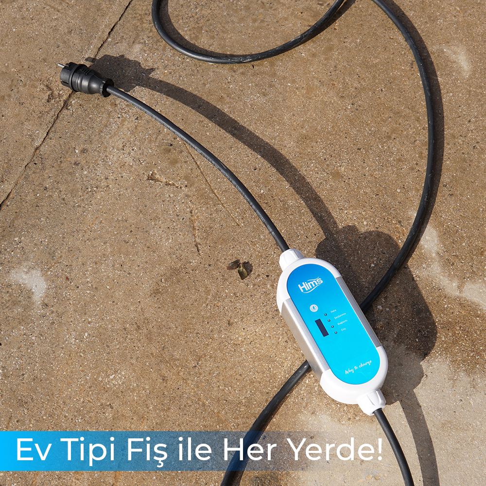 Beyaz ve mavi şarj adaptörlü siyah şarj kablosu beton zeminde duruyor.