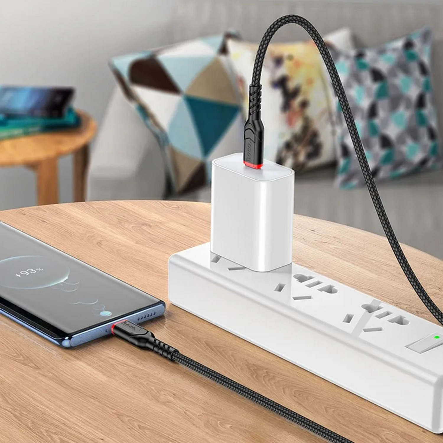Bir akıllı telefon, adaptörlü beyaz bir uzatma kablosuna bağlı siyah bir kabloyla şarj oluyor.
