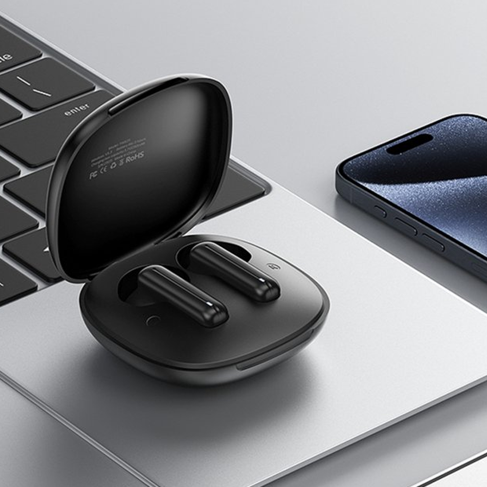 Auricolari wireless neri in custodia di ricarica su tastiera laptop accanto a smartphone.