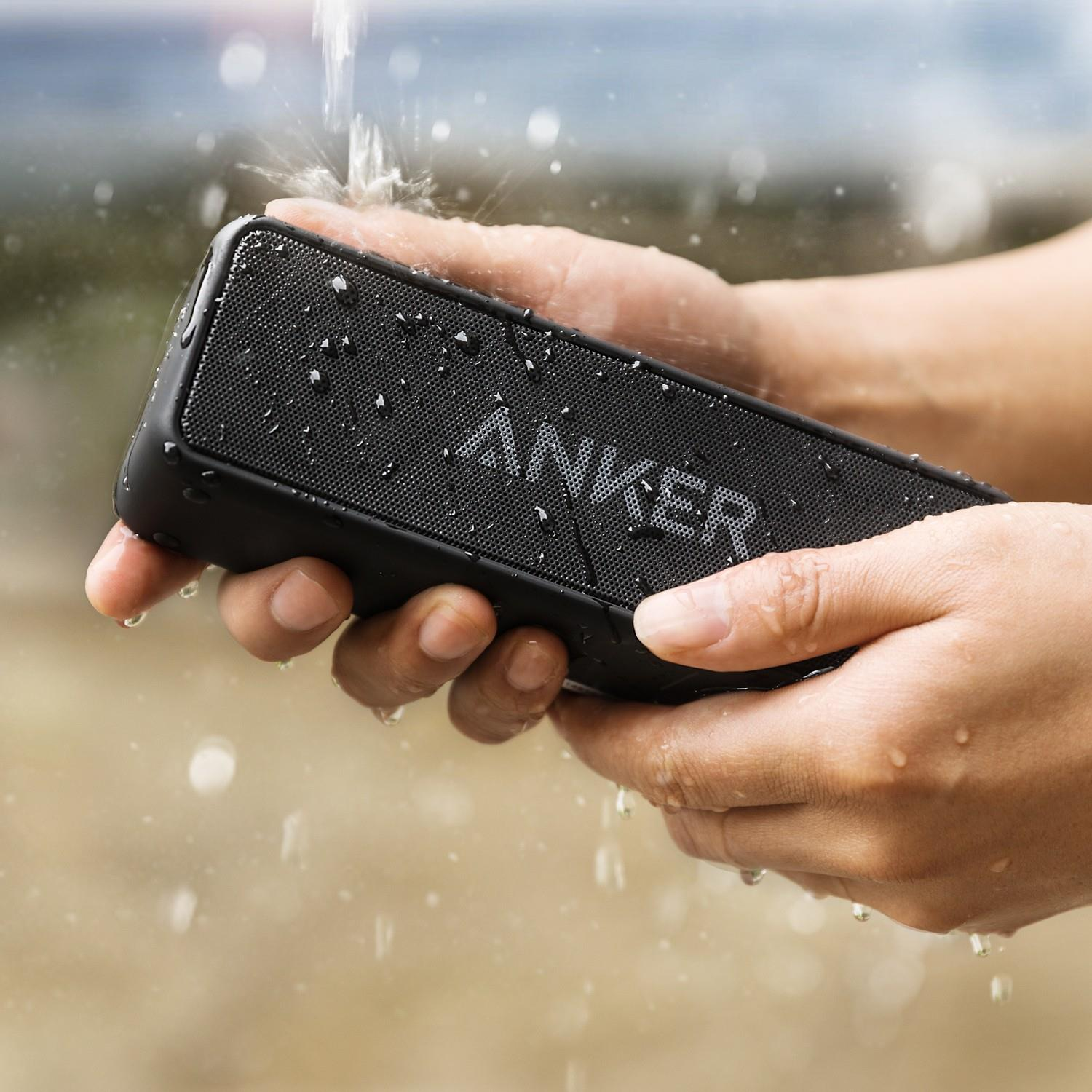 Altoparlante Anker nero tenuto sott'acqua, con gocce d'acqua.