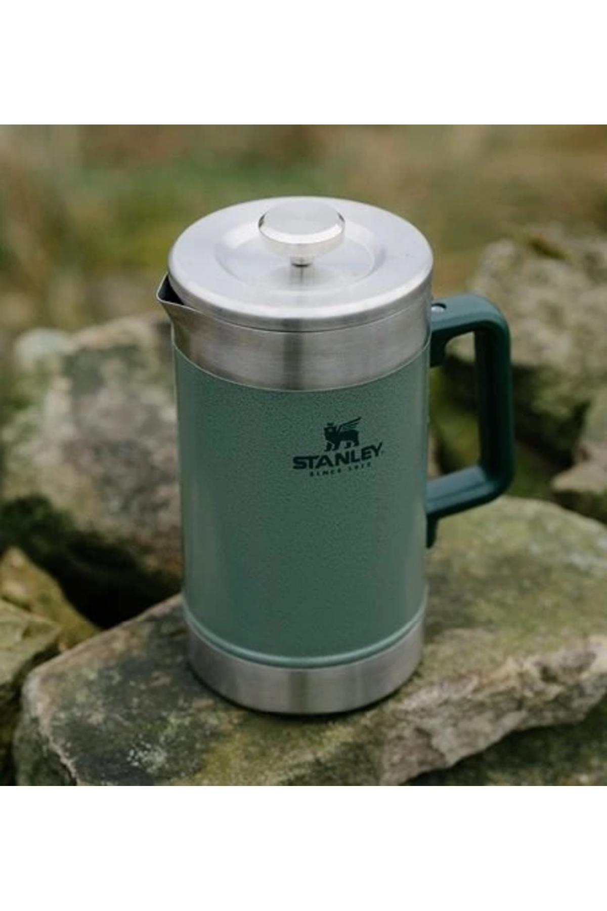 French press Stanley verde su rocce, con coperchio e manico argentati.