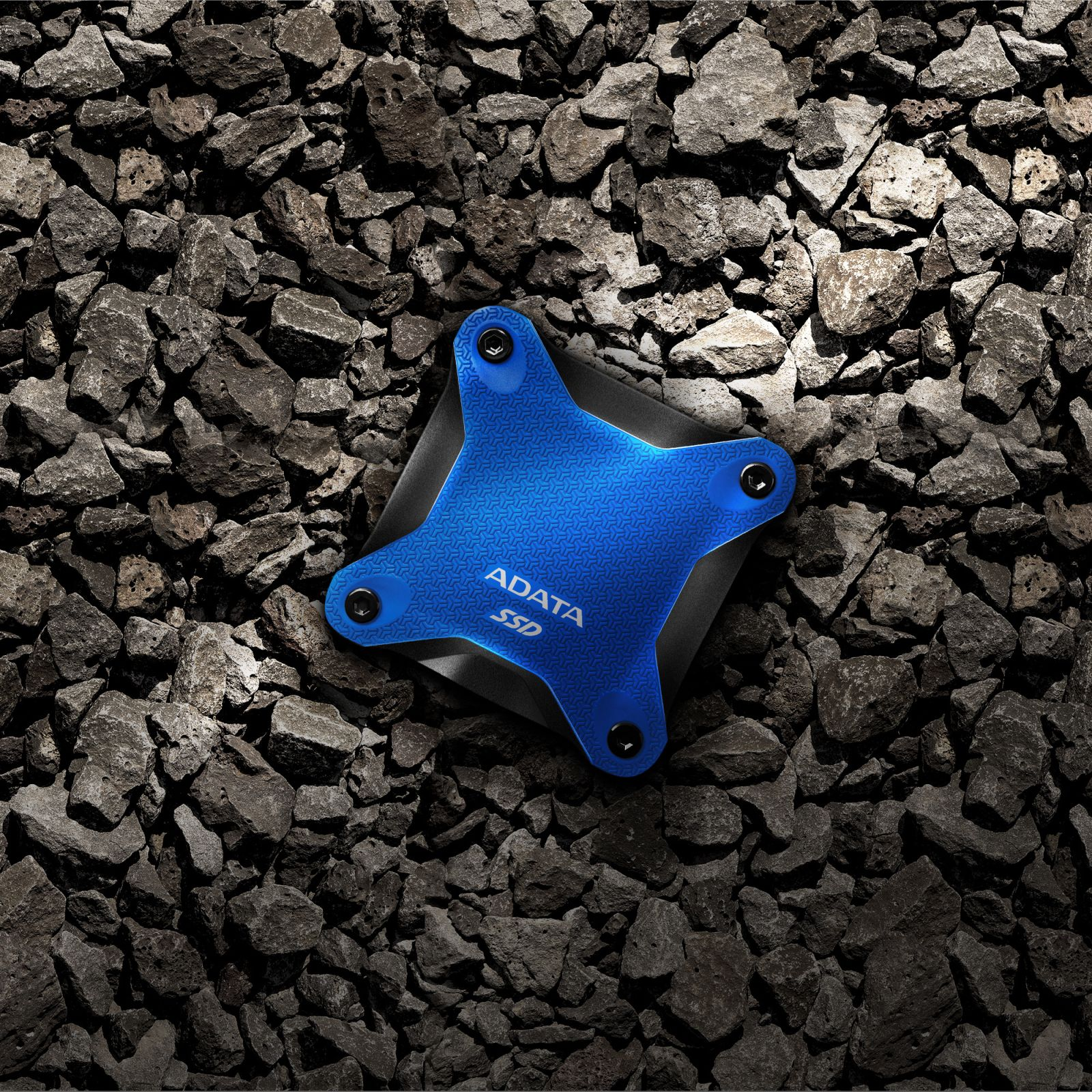 Niebieski dysk SSD ADATA leży na ciemnym żwirze.