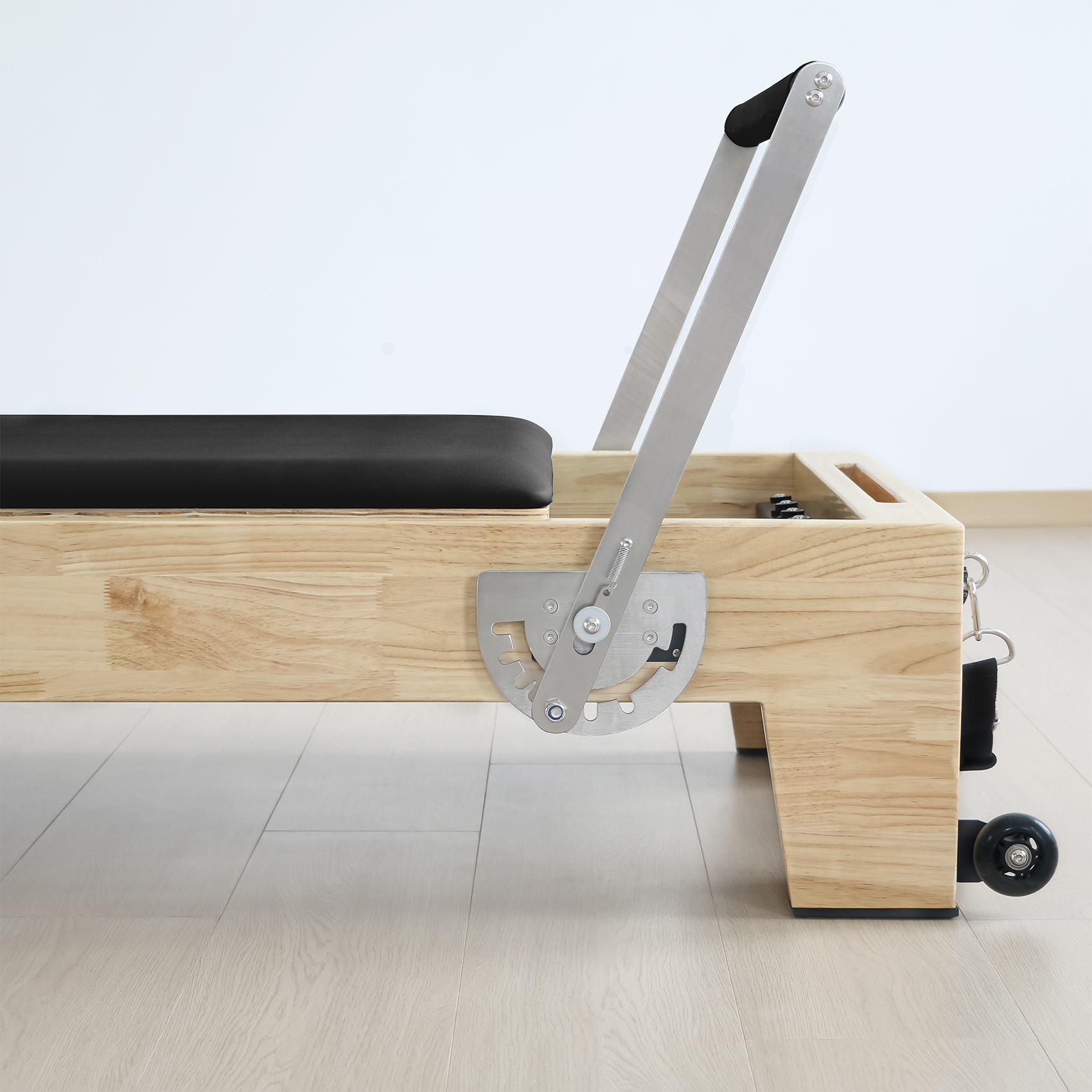 Ein hölzerner Pilates-Reformer mit schwarzem Polster und Metallteilen.