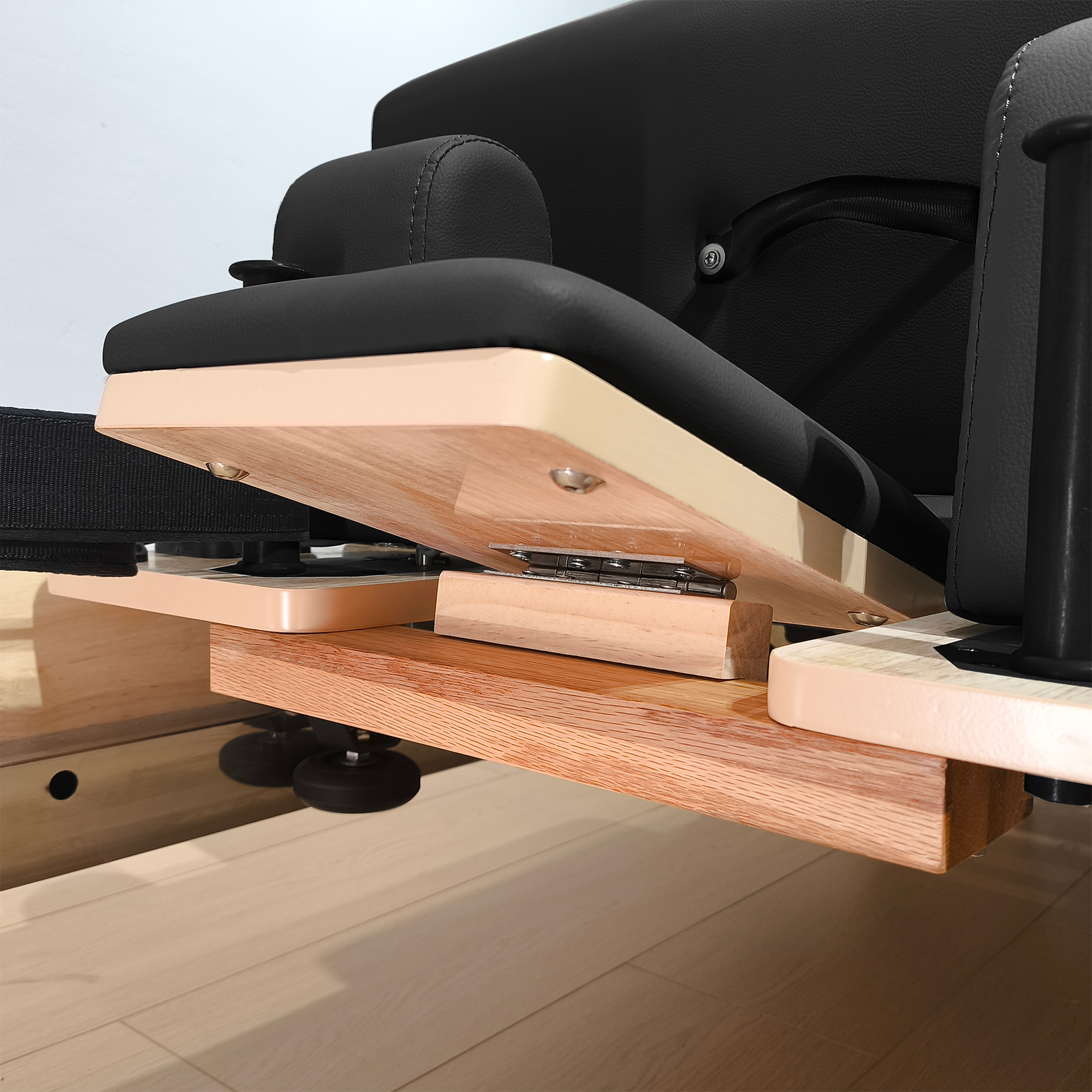Nahaufnahme eines Pilatesgeräts mit Holzelementen und schwarzer Polsterung.