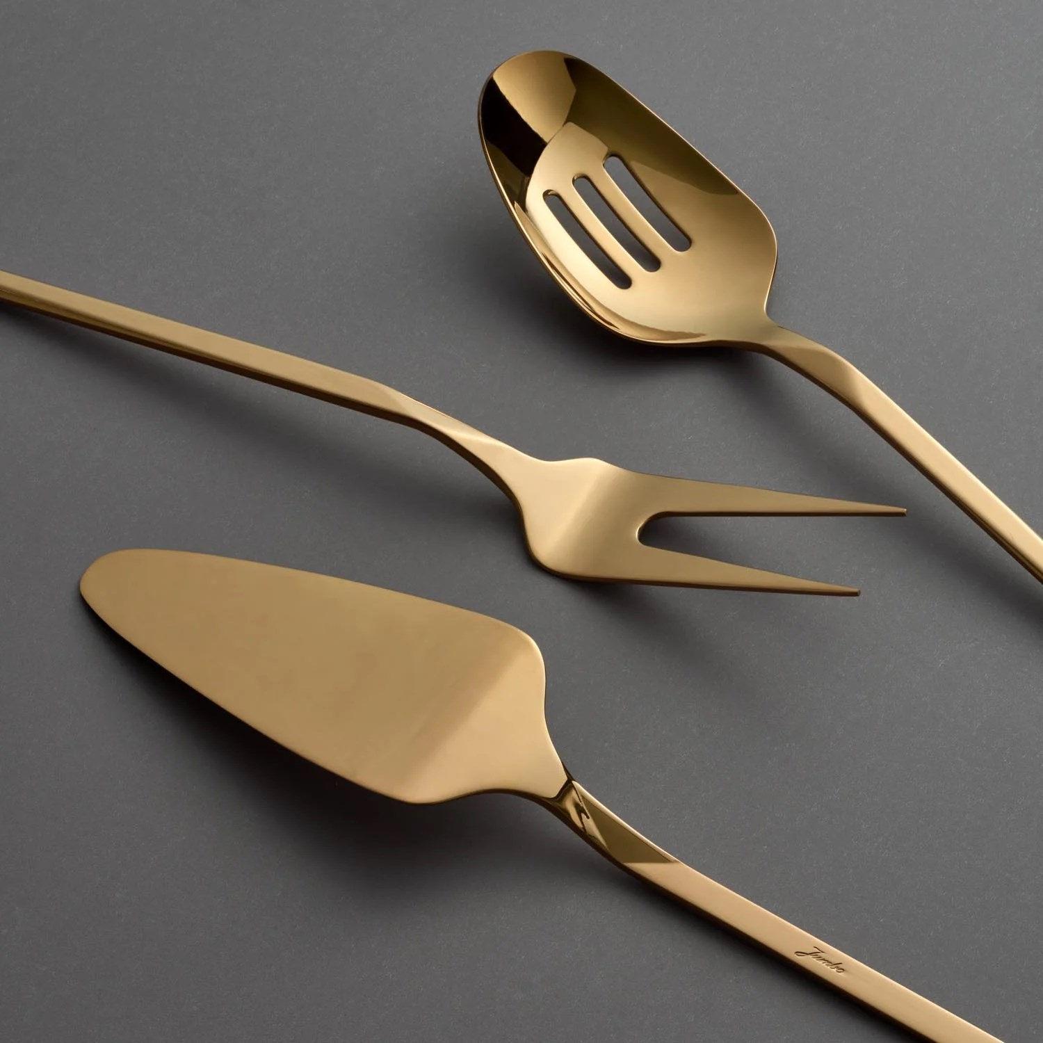 Altın rengi servis gereçleri: kaşık, çatal ve pasta spatulası.