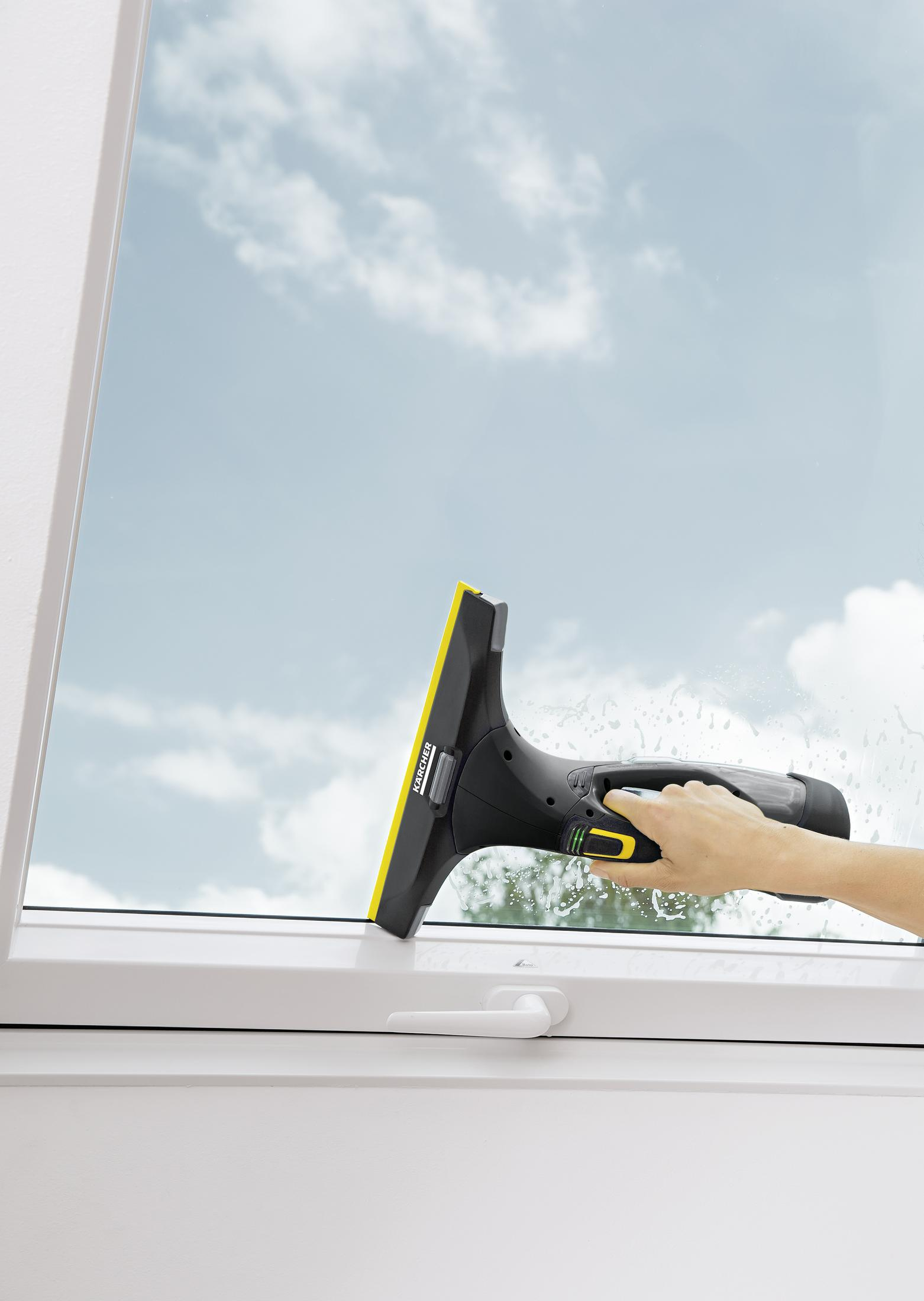 Ręka używa odkurzacza do okien Karcher do czyszczenia szyby.