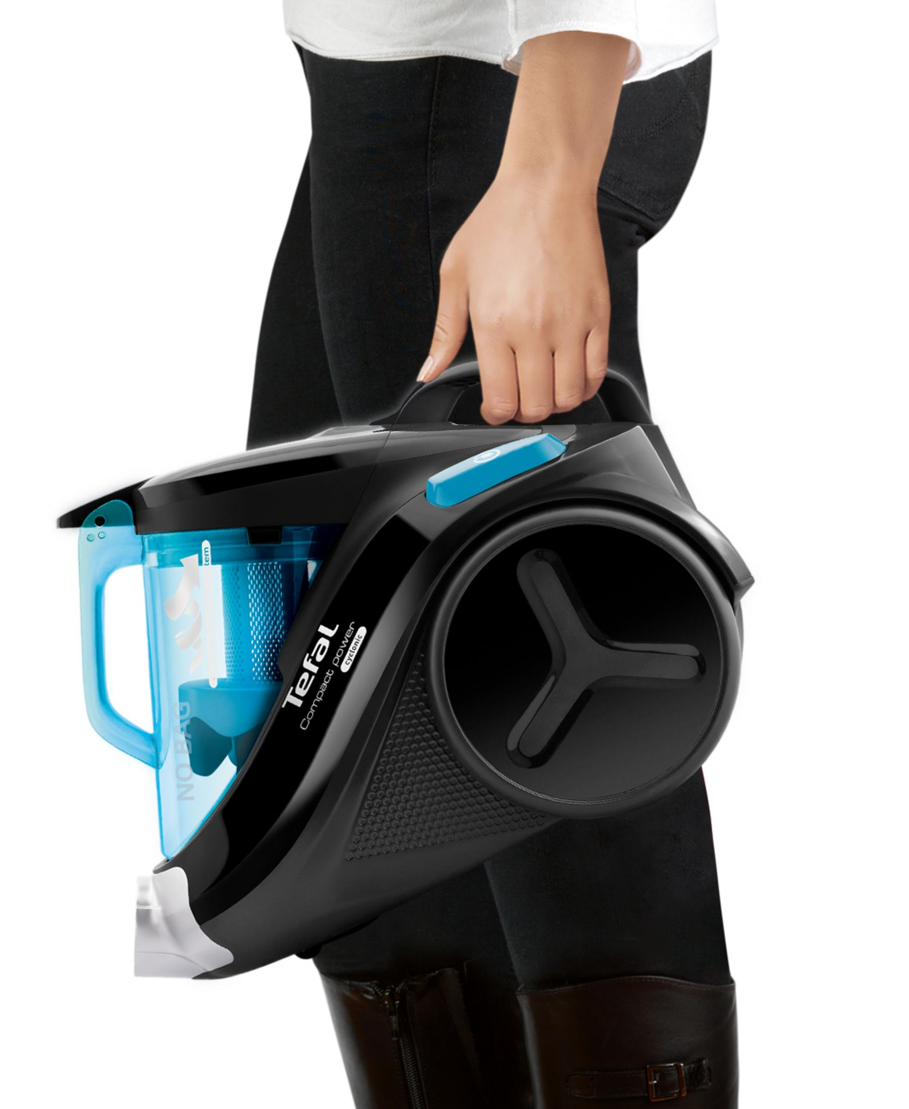 Şeffaf toz haznesi olan siyah ve mavi Tefal elektrikli süpürge tutan kişi.