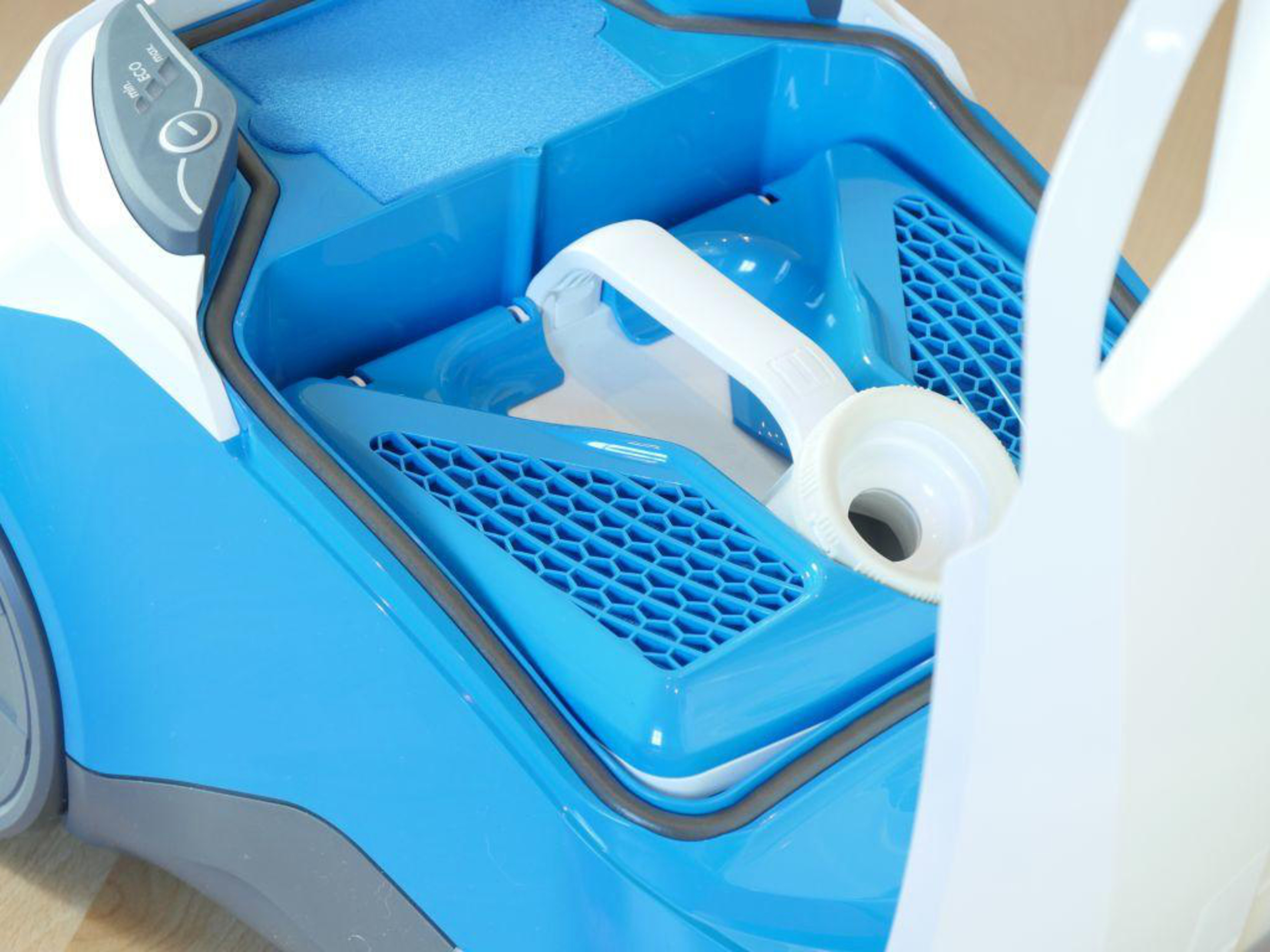 Niebiesko-biały odkurzacz z otwartym pojemnikiem i uchwytem.