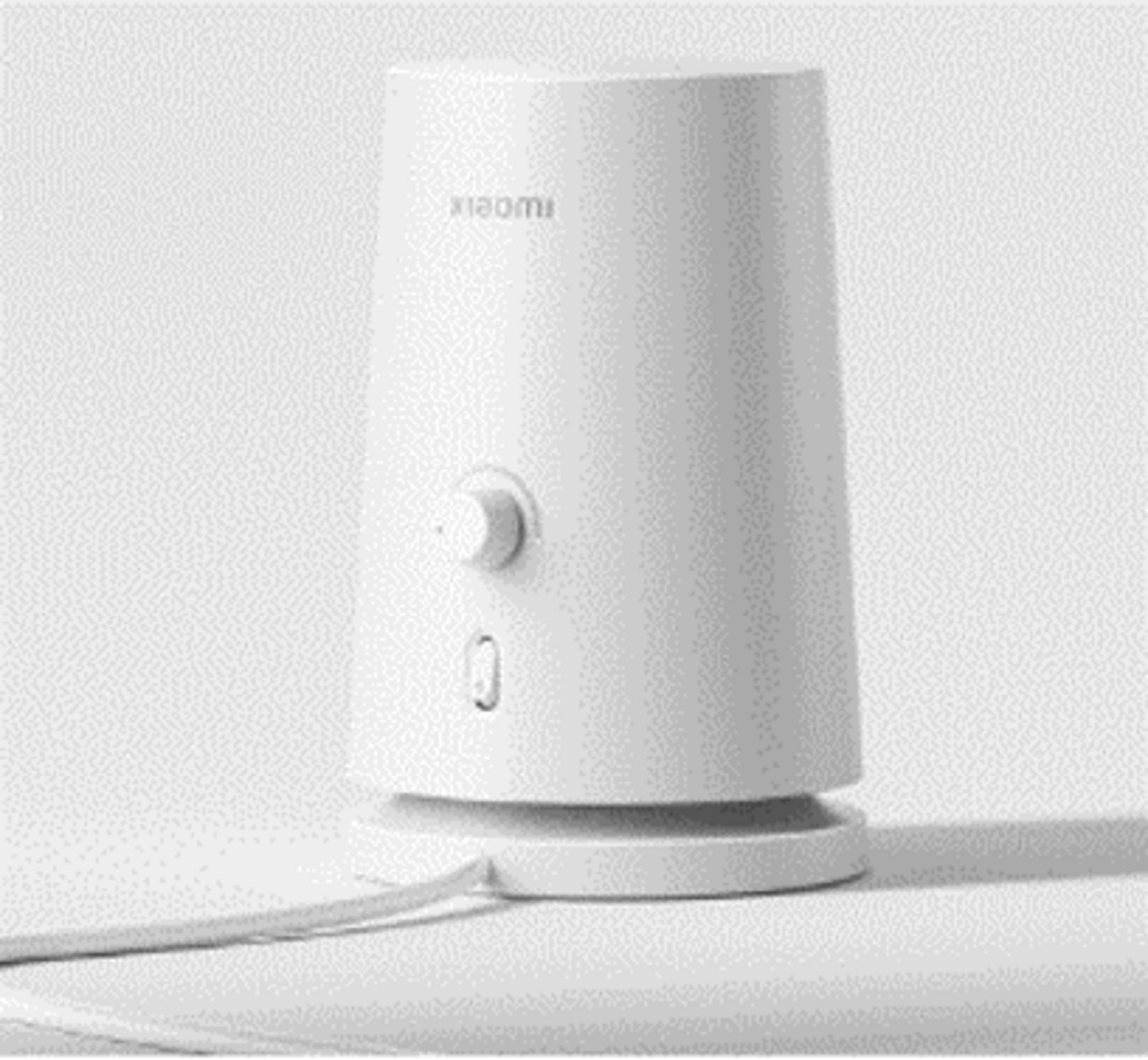 Düğmeli ve küçük delikli beyaz bir Xiaomi cihazı taban üzerinde duruyor.