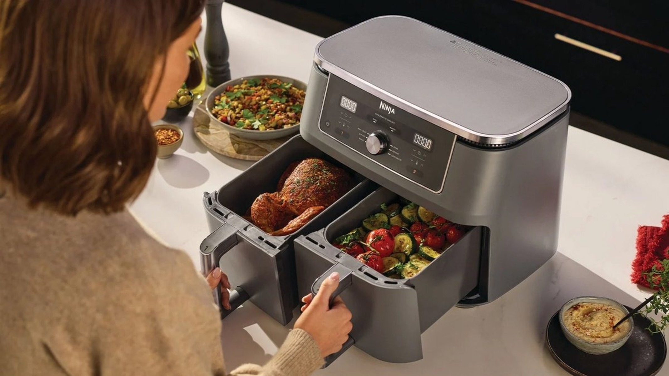 Podwójna frytkownica beztłuszczowa Ninja z kurczakiem w jednej szufladzie i warzywami w drugiej.