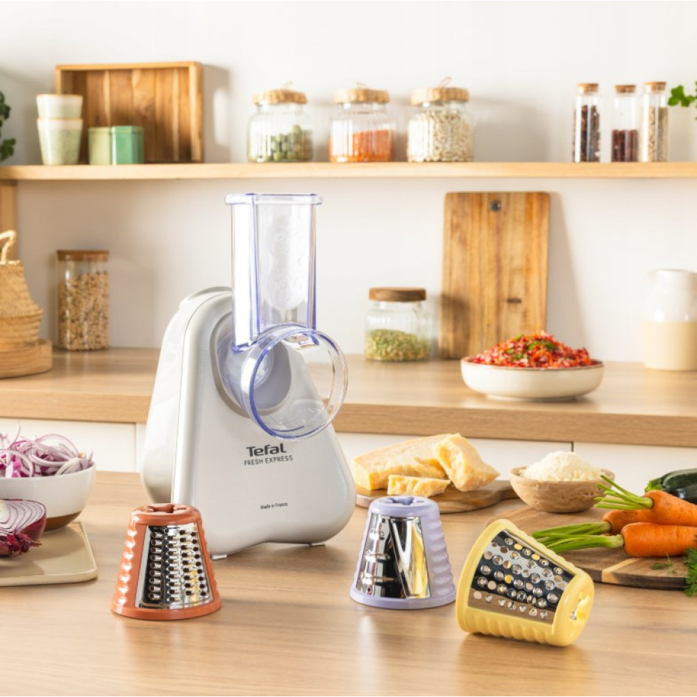 Biała tarka Tefal z pomarańczowymi, fioletowymi i żółtymi nasadkami stoi na drewnianym blacie.