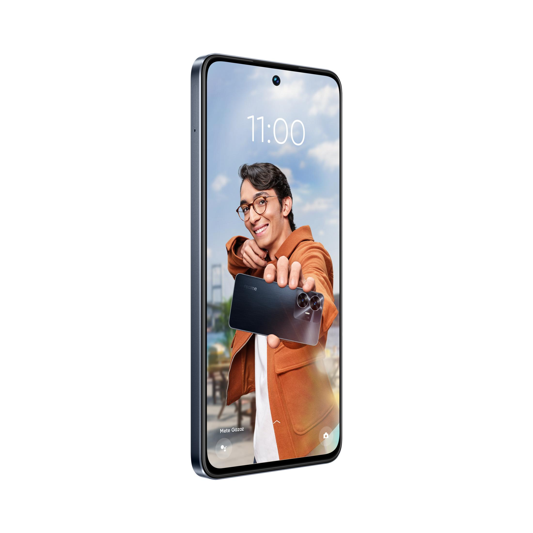 Gözlüklü bir adam, karanlık bir akıllı telefonu kameraya doğru tutuyor. Gökyüzü bulutlu ve mavidir.