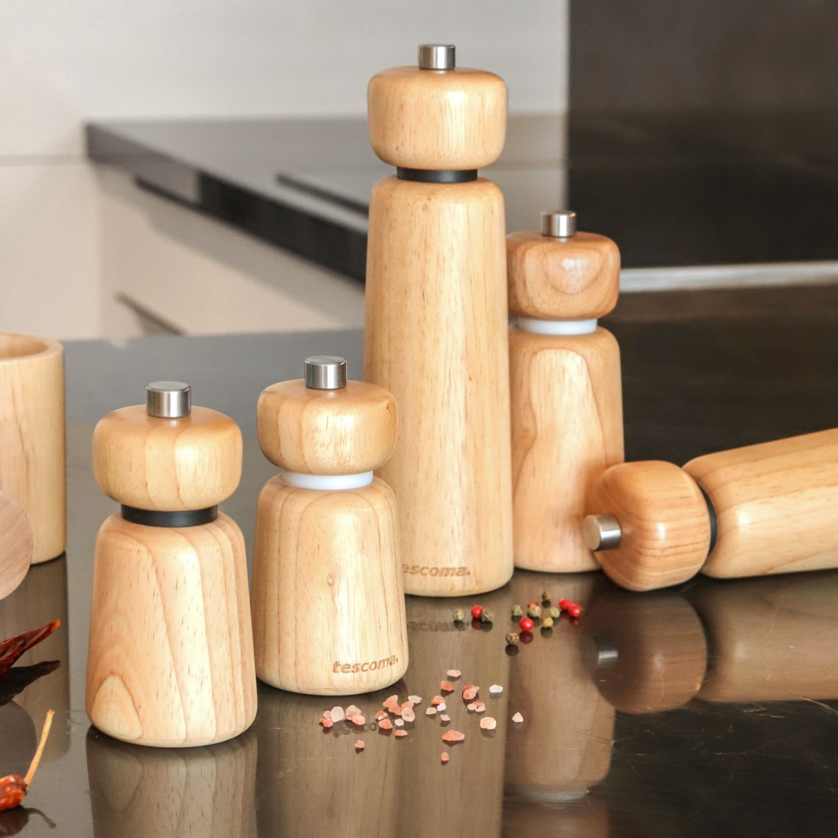 Holzmühlen für Gewürze, einige aufrecht, eine liegend, mit Salz und Pfefferkörnern.