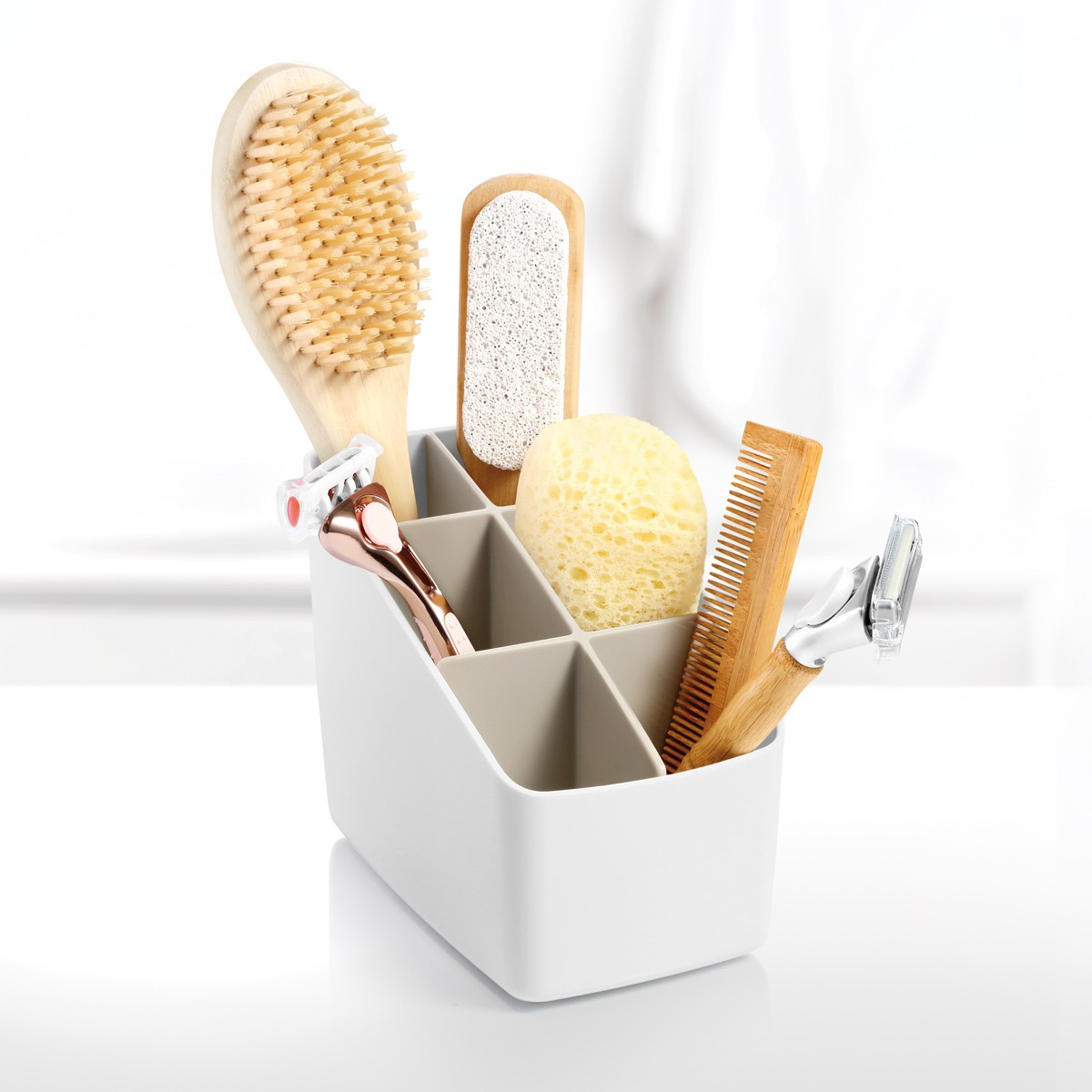 Ein grauer Organizer mit Badezubehör: Bürste, Bimsstein, Schwamm, Kamm und Rasierer.