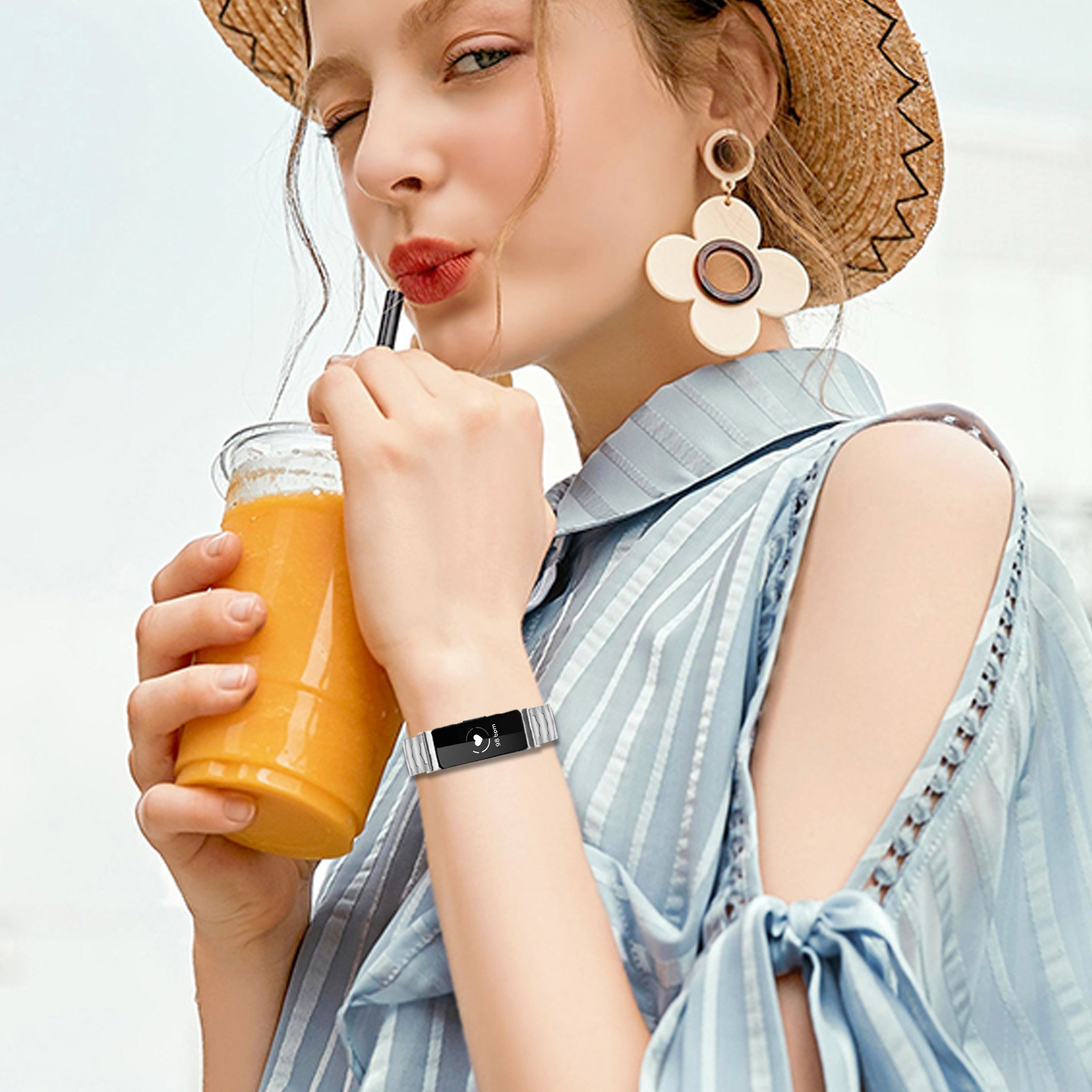 Eine Frau mit Strohhut trinkt aus einem Glas Orangensaft.