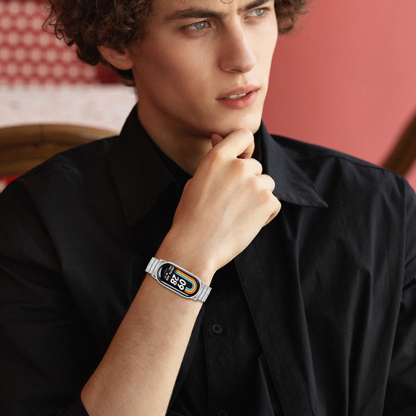 Ein Mann mit lockigem Haar trägt ein schwarzes Hemd mit einer Smartwatch.