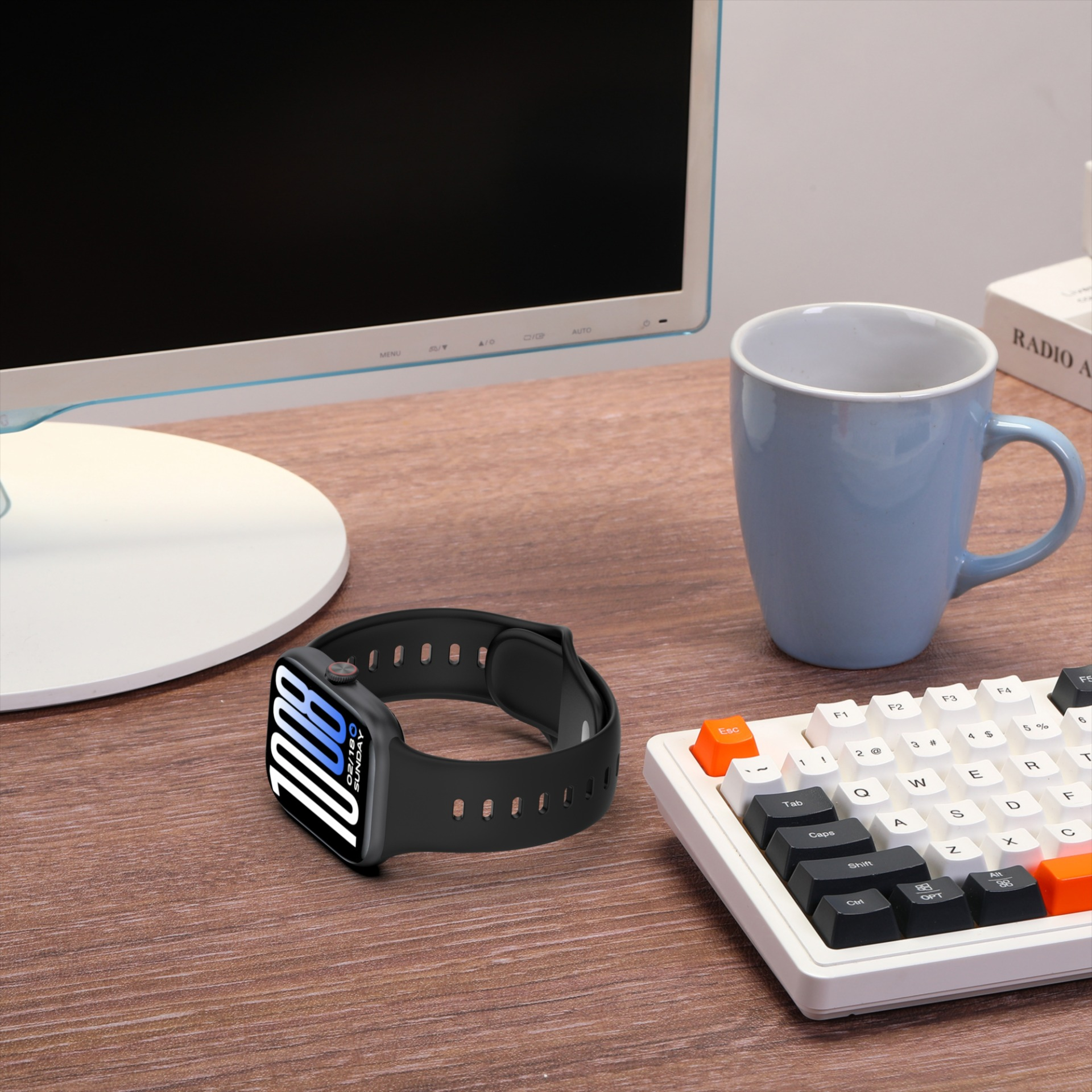 Eine schwarze Smartwatch mit blauem Zifferblatt liegt auf einem Holztisch neben einer Tastatur.