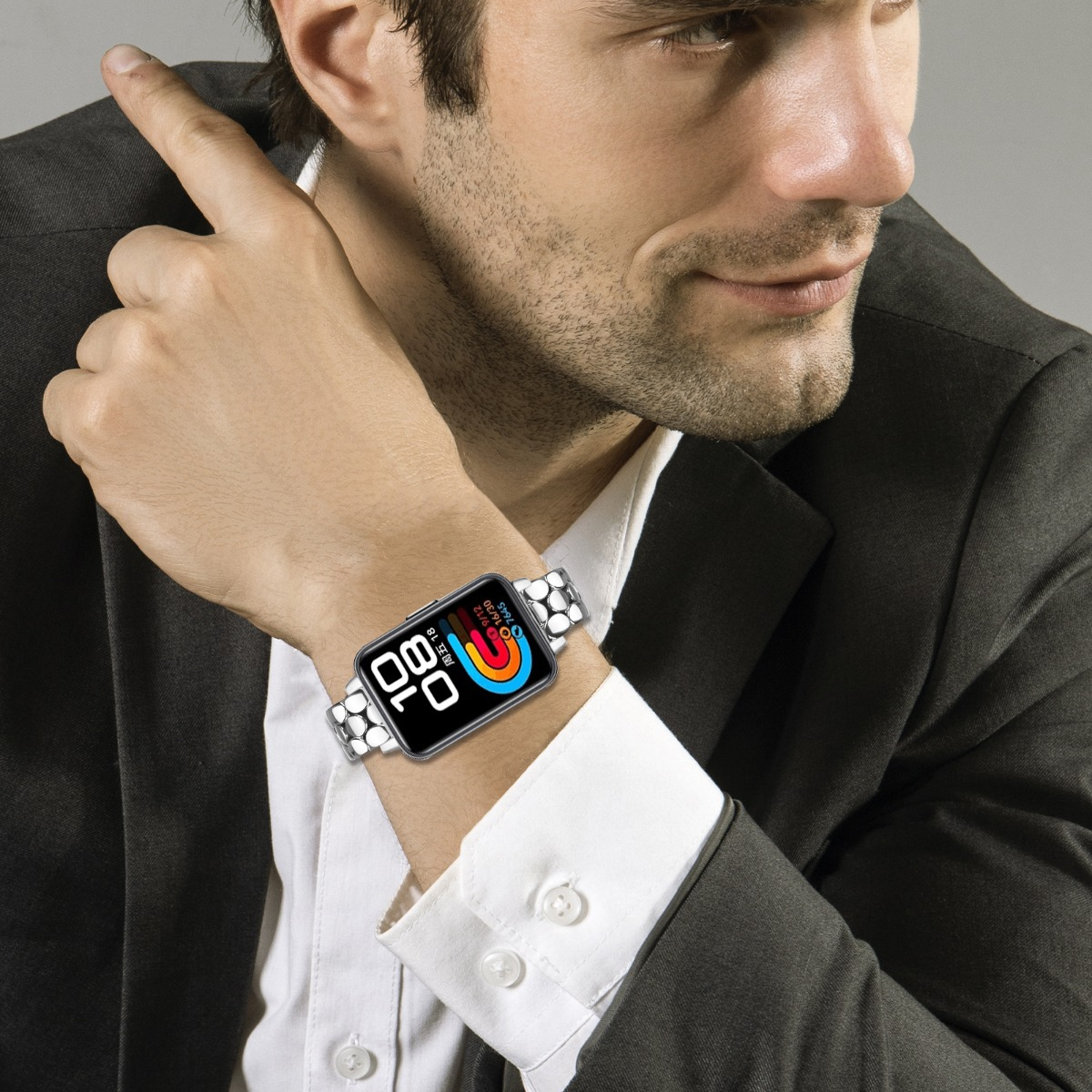 Uomo con giacca nera e camicia bianca, mostra il suo smartwatch al polso sinistro.