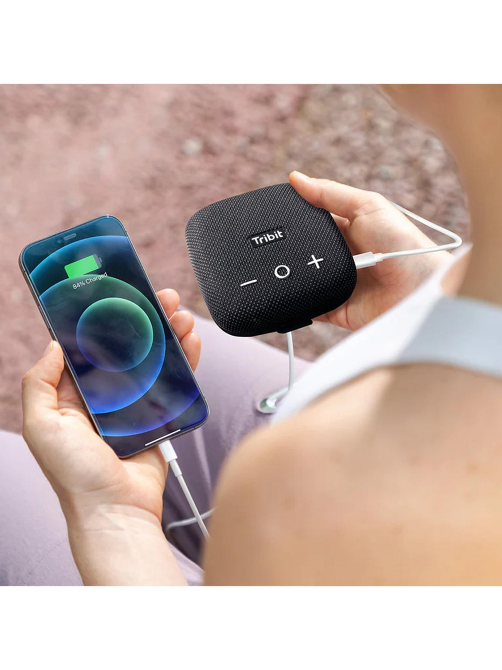 Person lädt ein Smartphone mit einem Tribit-Lautsprecher auf.