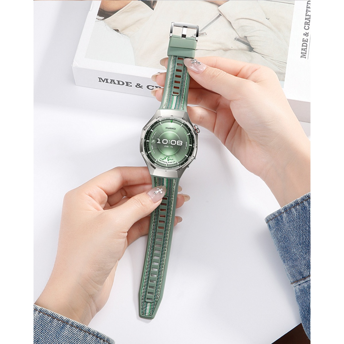 Grüne Smartwatch mit silbernem Gehäuse, gehalten von zwei Händen.