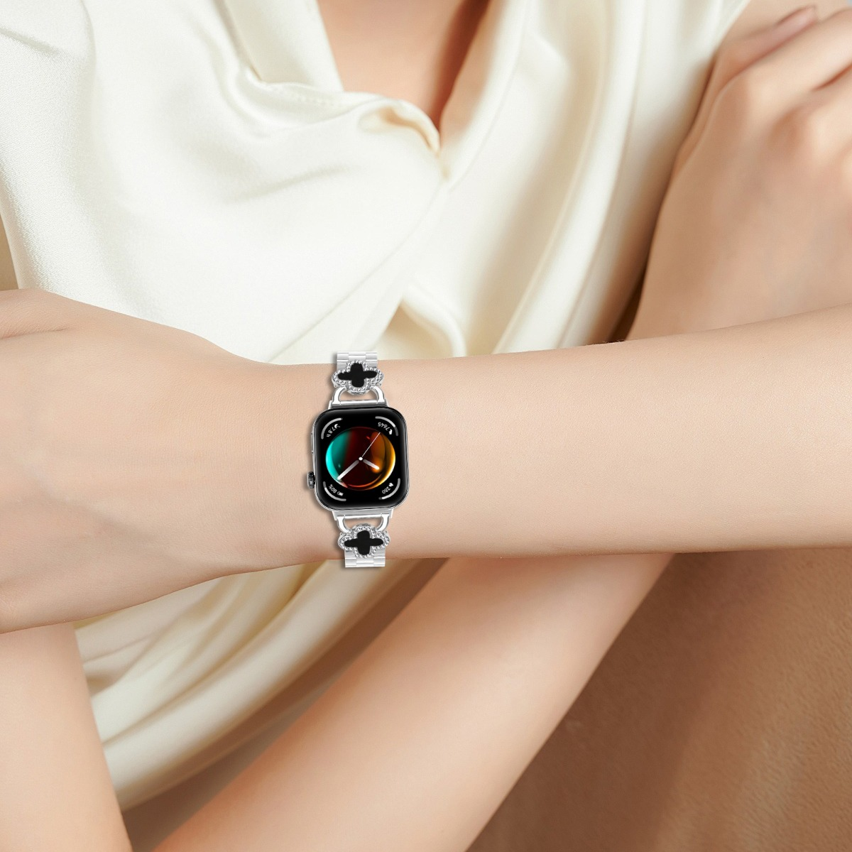 Eine Frau trägt eine Smartwatch mit einem silbernen Armband mit Kleeblatt-Motiven.