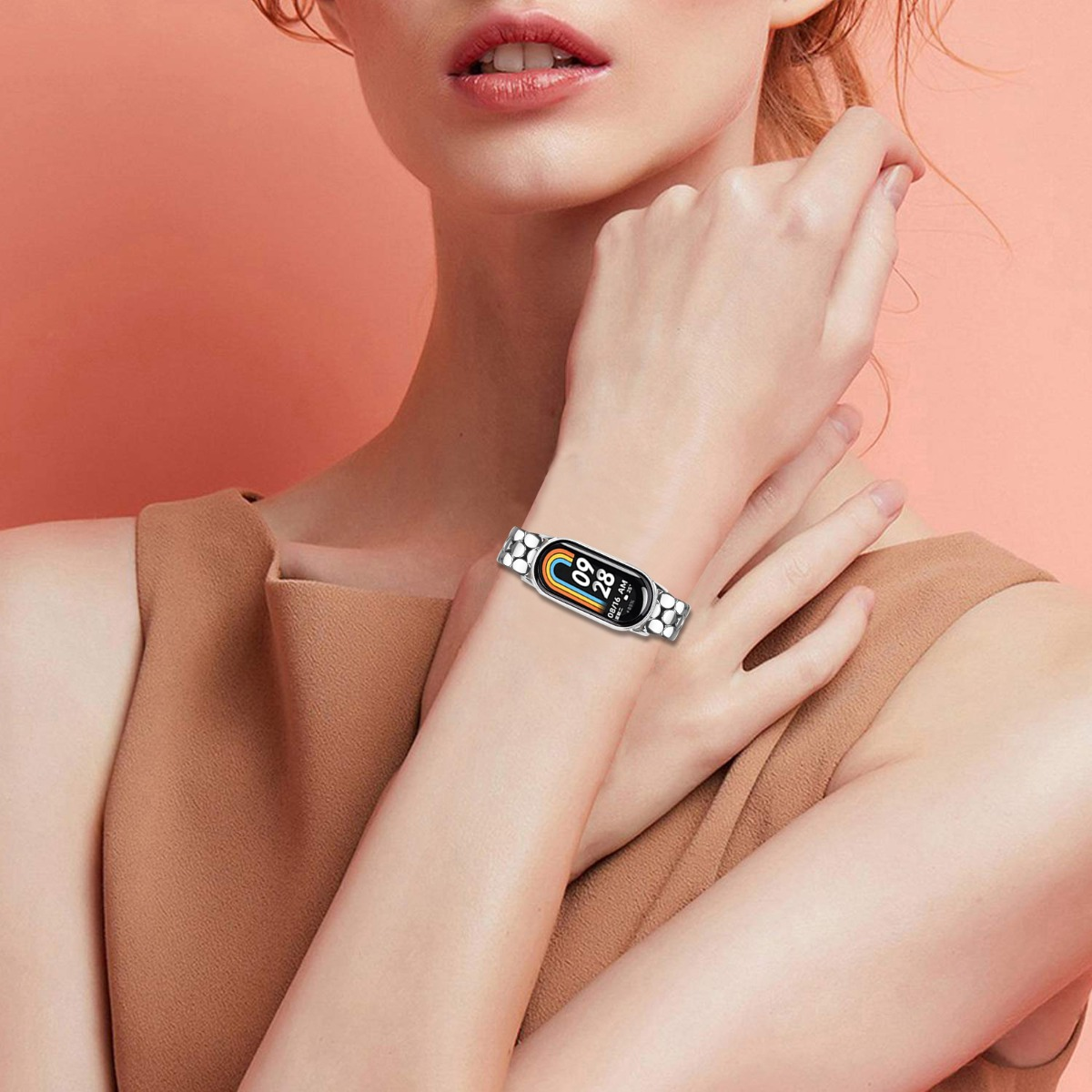 Eine Frau trägt ein silbernes Armband mit einem Fitness-Tracker. Der Bildschirm zeigt Zeit und Datum.