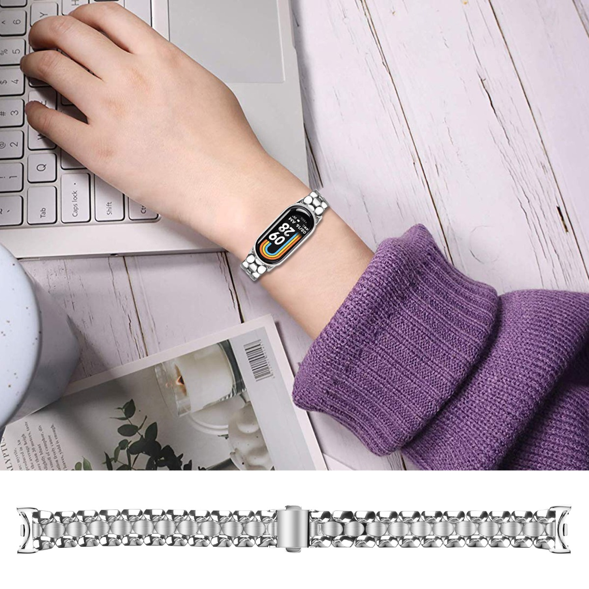 Eine Person trägt ein silbernes Armband an einem Smartwatch, die auf einem Laptop tippt.
