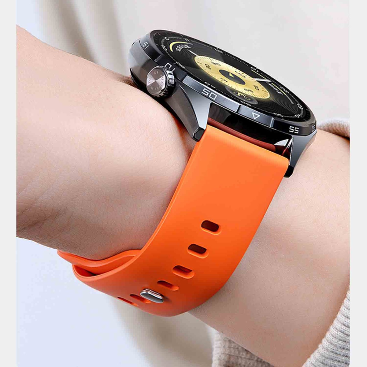 Uno smartwatch arancione con cassa nera e quadrante giallo indossato al polso.