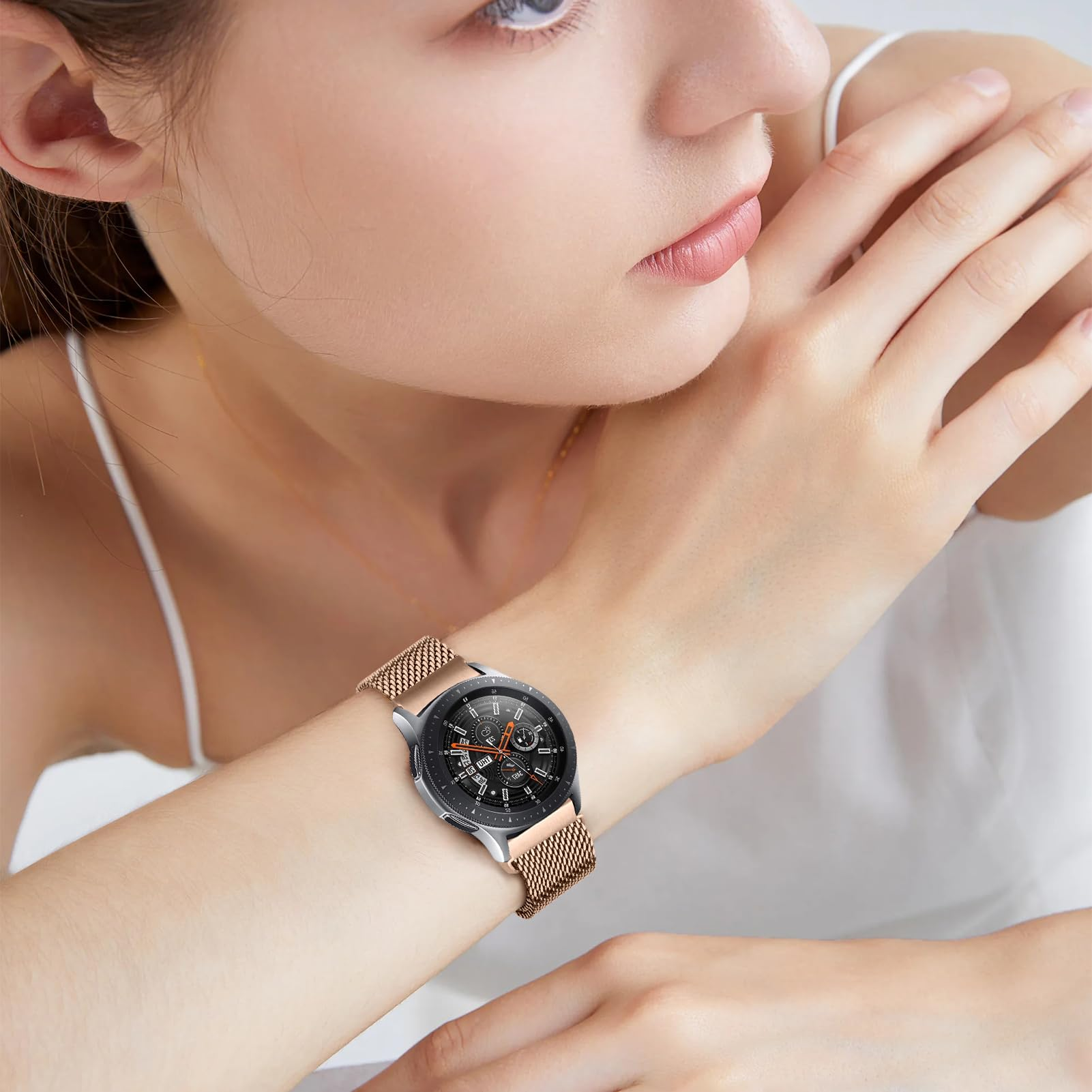 Eine Frau trägt ein silbernes Smartwatch mit einem roséfarbenen Mesh-Armband.