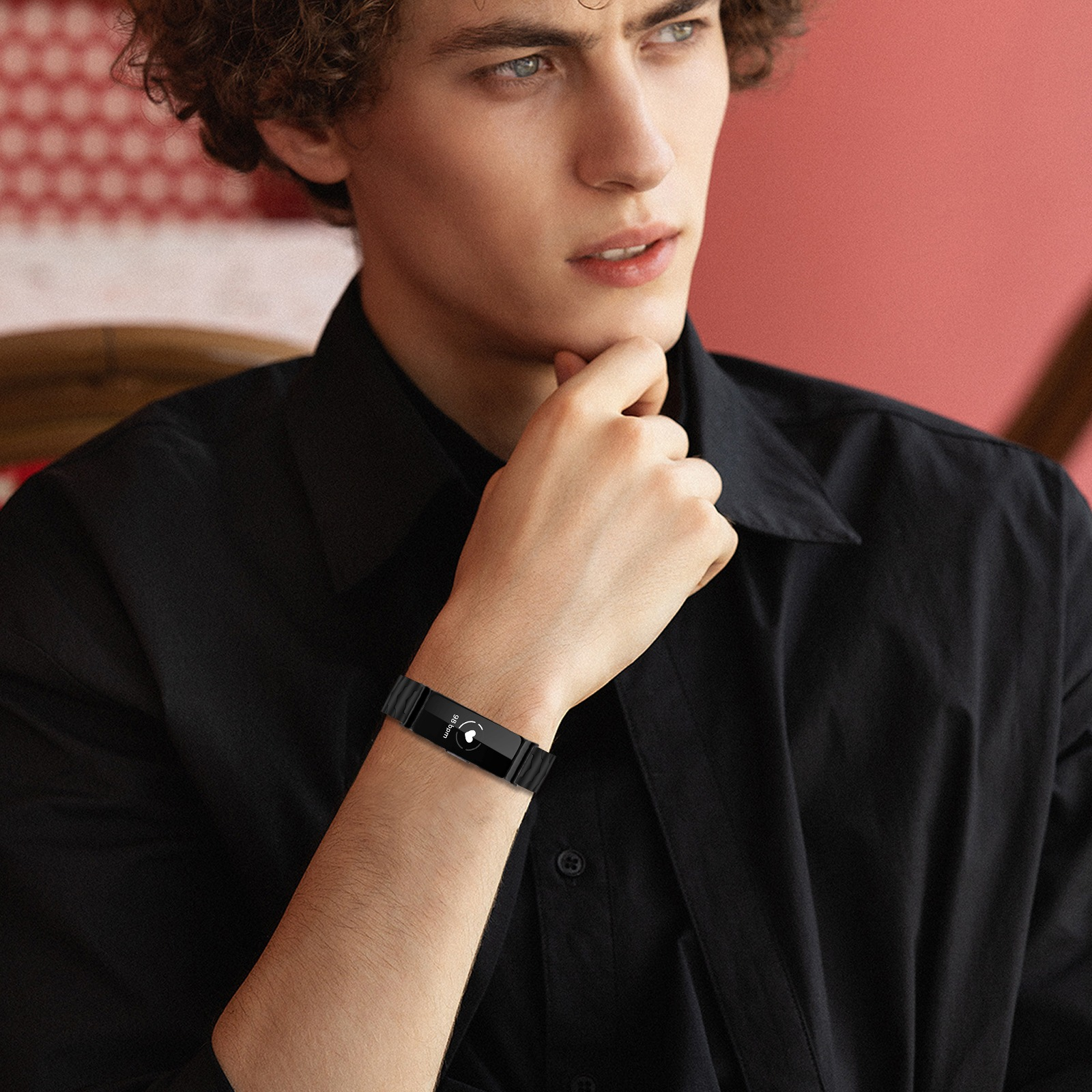 Ein Mann mit lockigem Haar trägt ein schwarzes Hemd und eine Smartwatch am Handgelenk.