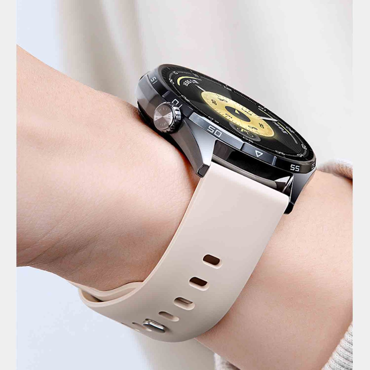 Eine graue Smartwatch mit beigem Armband an einem Handgelenk.