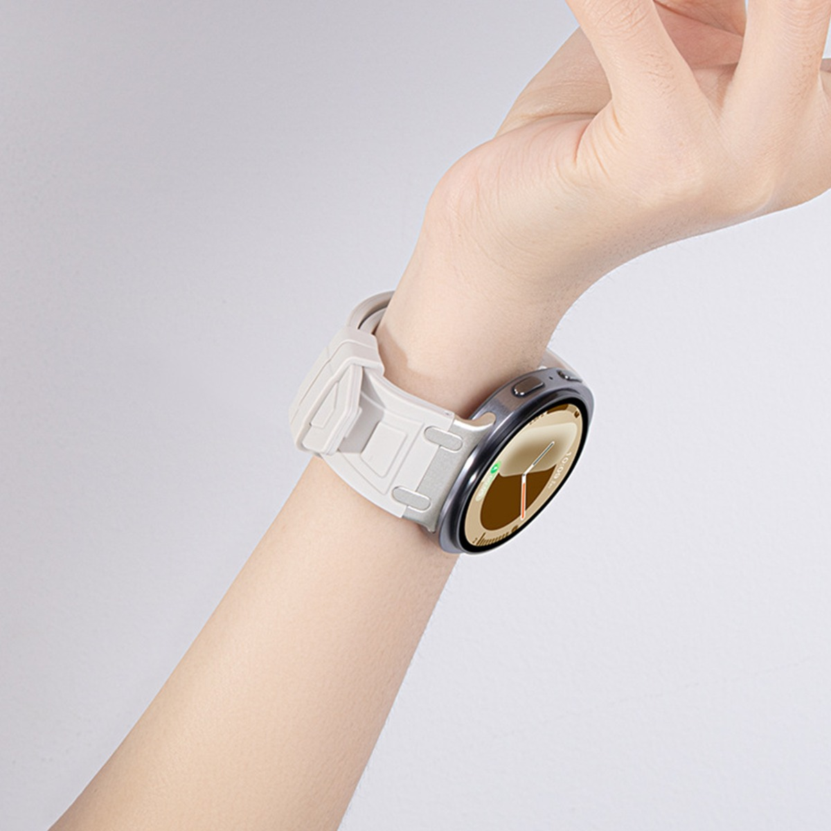 Un polso umano indossa uno smartwatch grigio con cinturino beige chiaro.