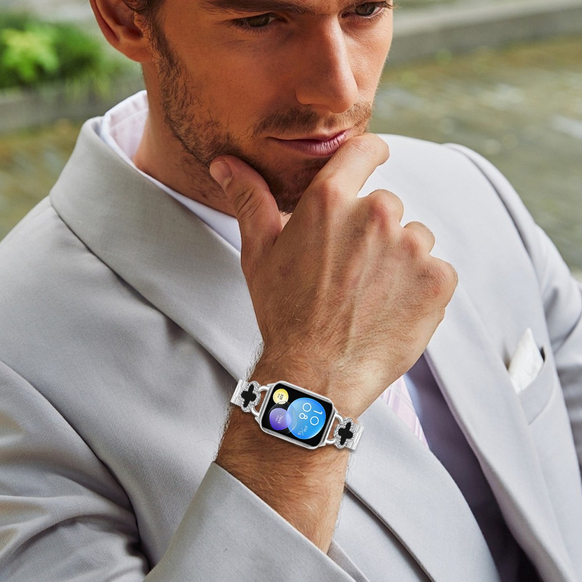 Mann im grauen Anzug mit einer Smartwatch am Handgelenk, die 10:08 Uhr anzeigt.