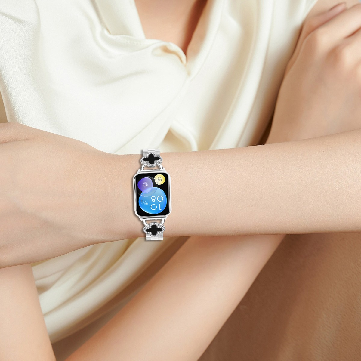 Eine Frau trägt ein Smartwatch mit einem silbernen Armband mit Kleeblatt-Motiv.