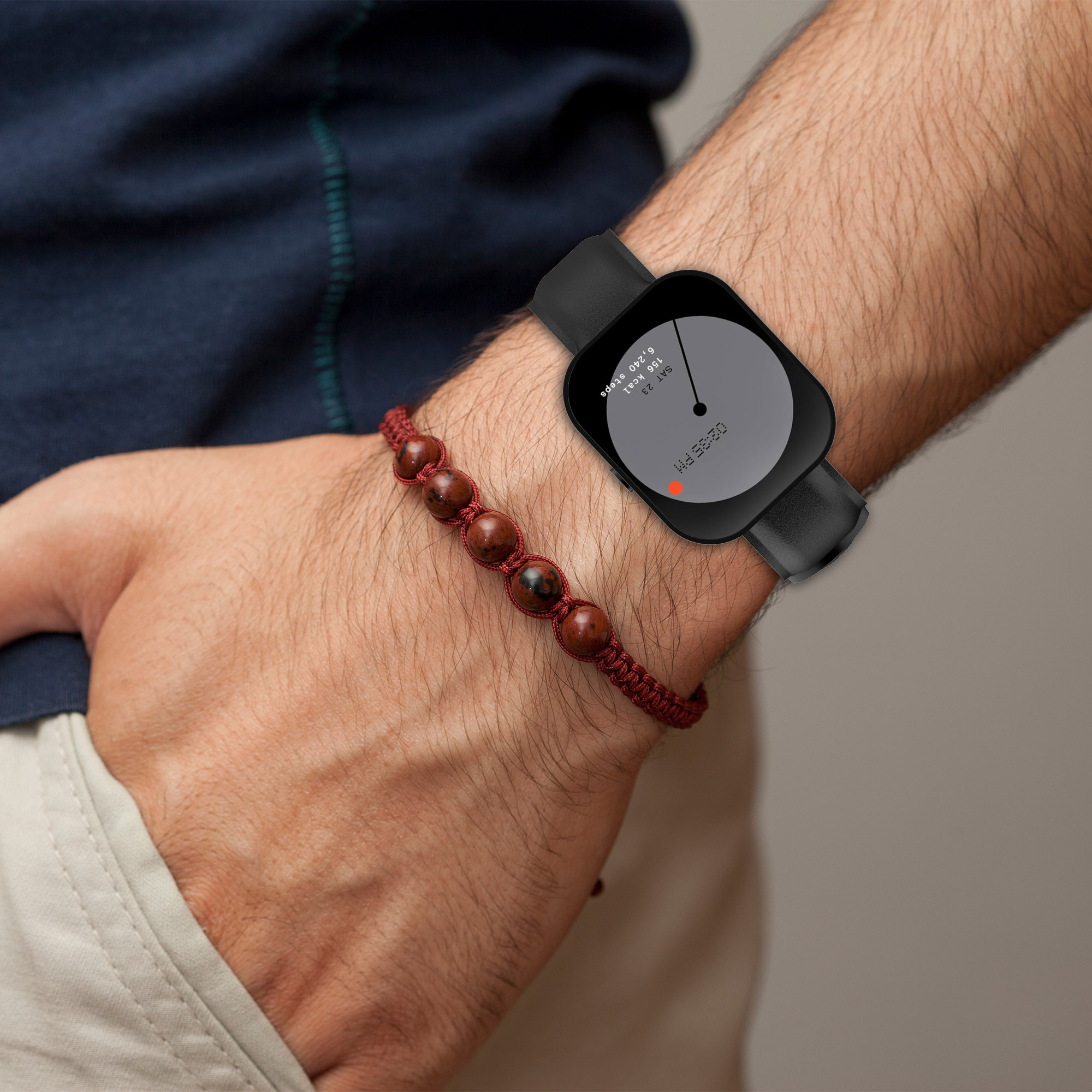 Ein Arm mit einer Smartwatch und einem braunen Perlenarmband.