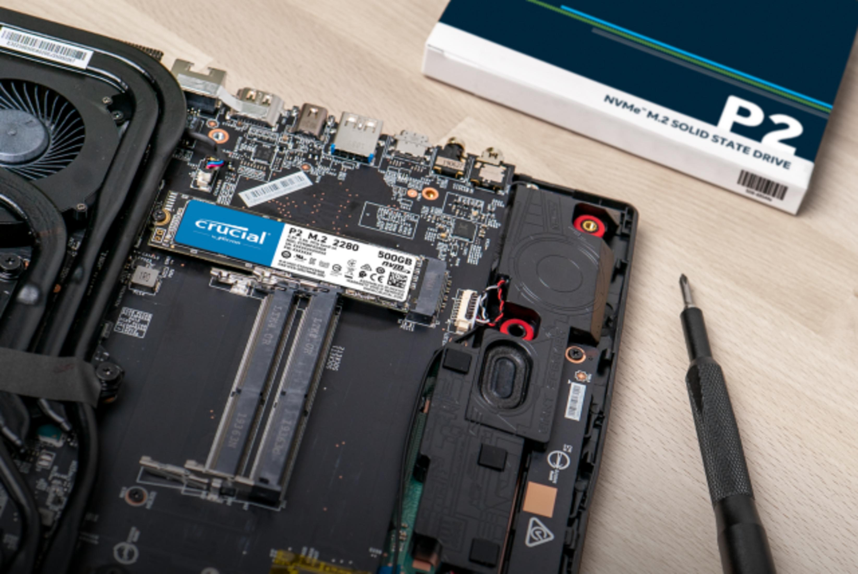 Ein Laptop-Motherboard mit installierter SSD und Lüfter. Daneben eine SSD-Verpackung.