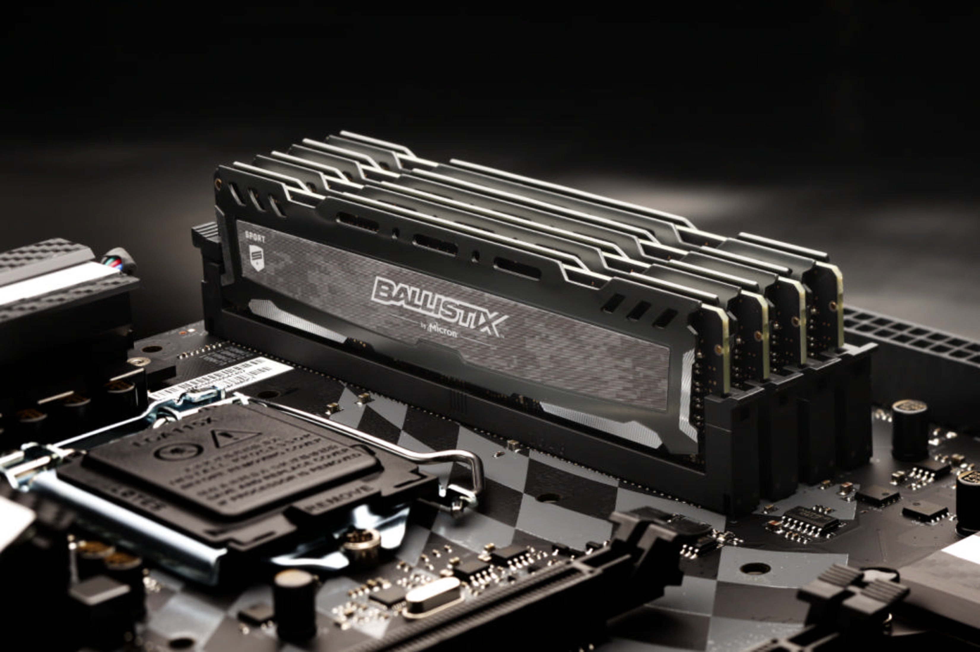 Ballistix RAM modules on a motherboard against a dark background.