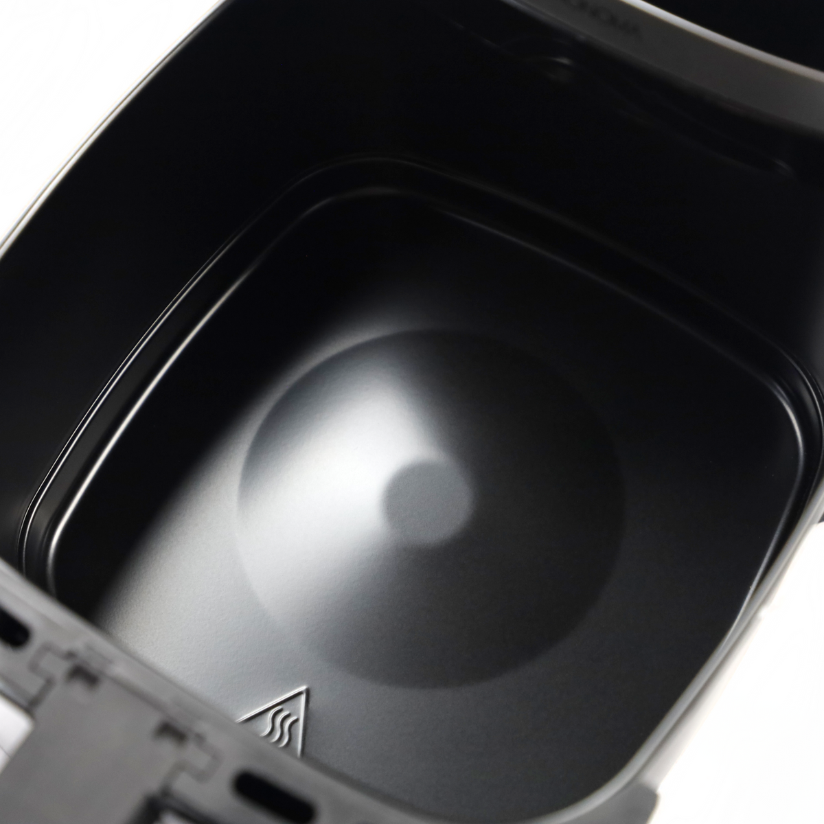 Zbliżenie czarnego kosza frytkownicy beztłuszczowej z teksturowanym dnem i błyszczącymi krawędziami.