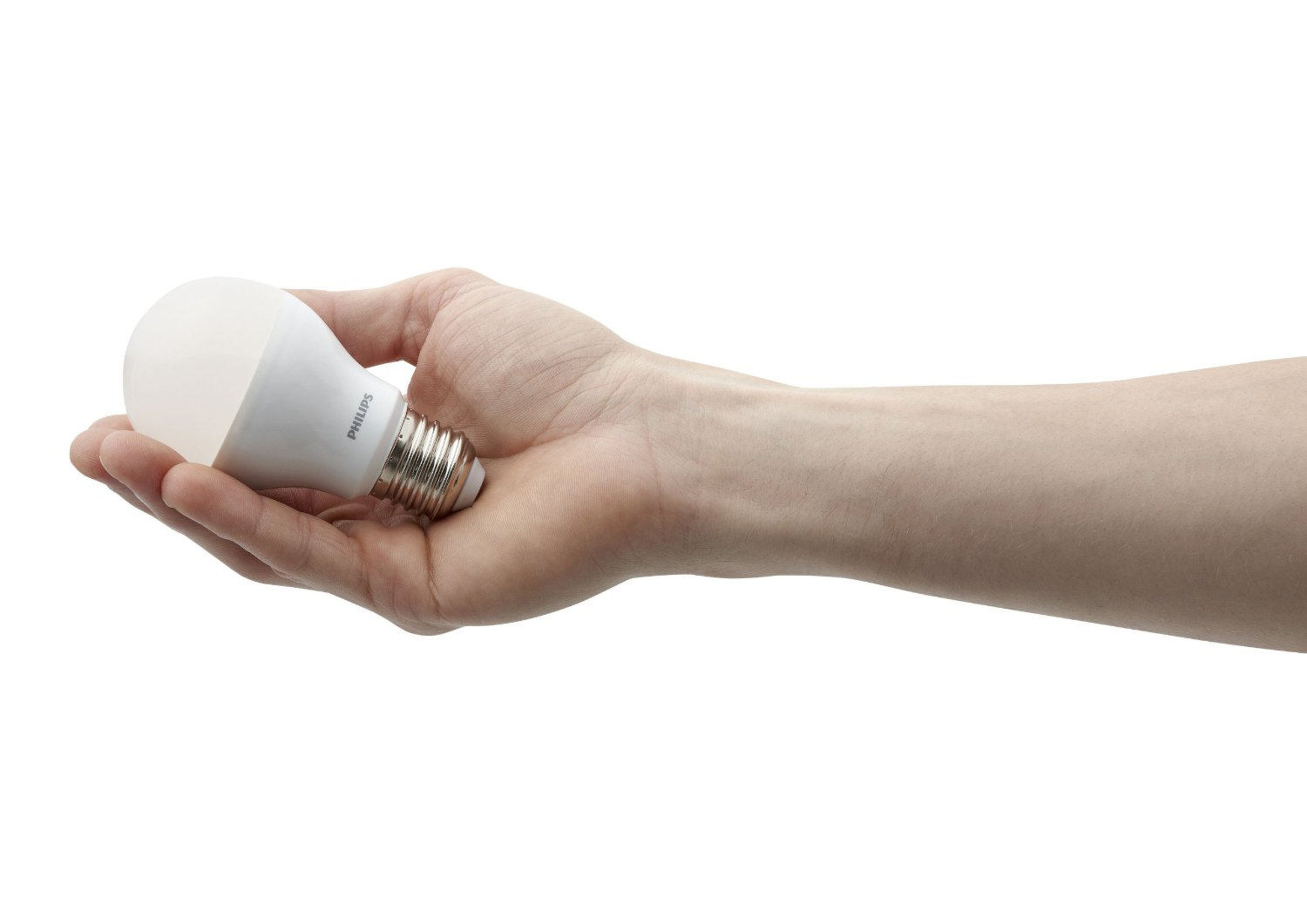 Una mano sostiene una bombilla LED Philips blanca.